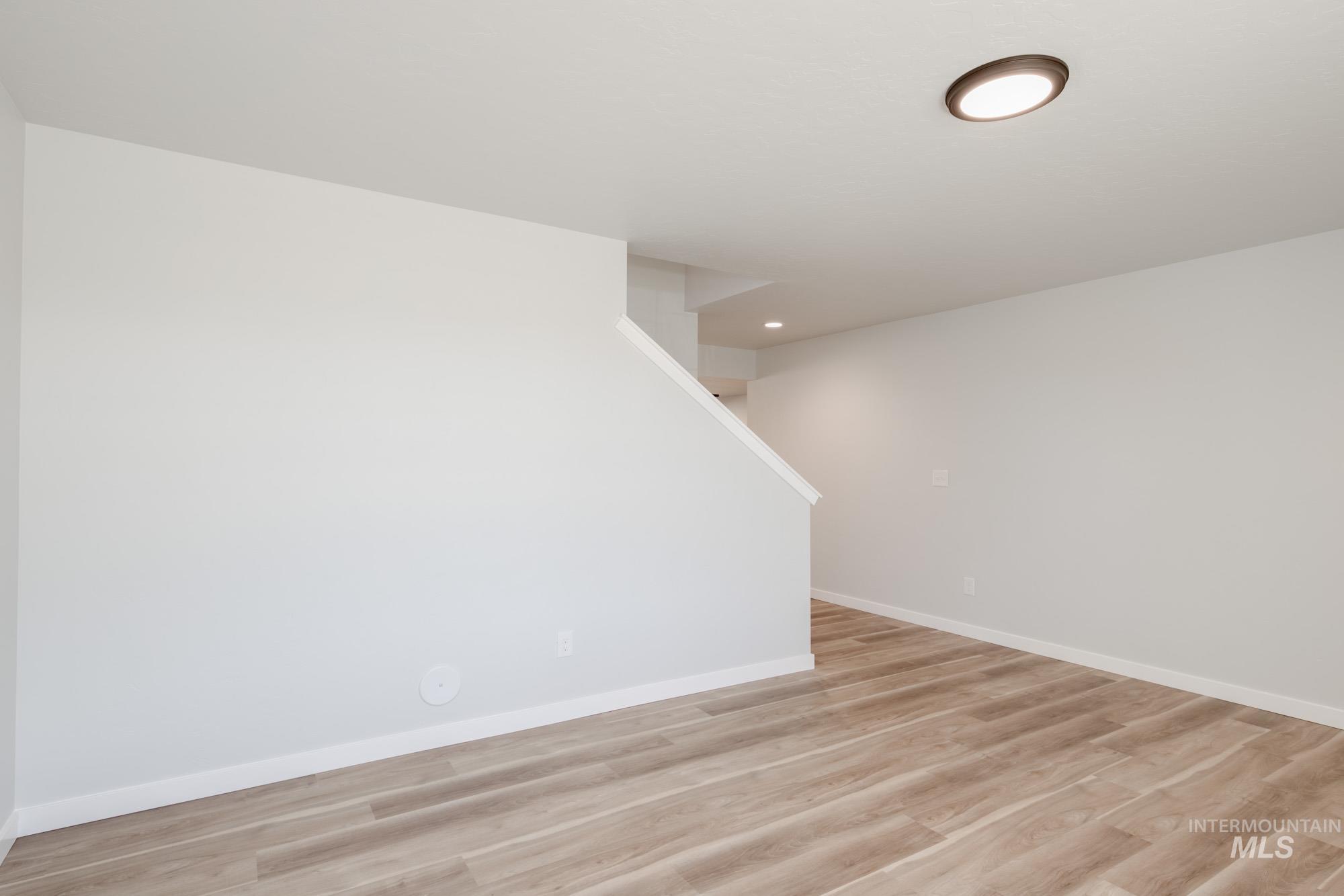 Empty room with light wood finished floors and recessed lighting