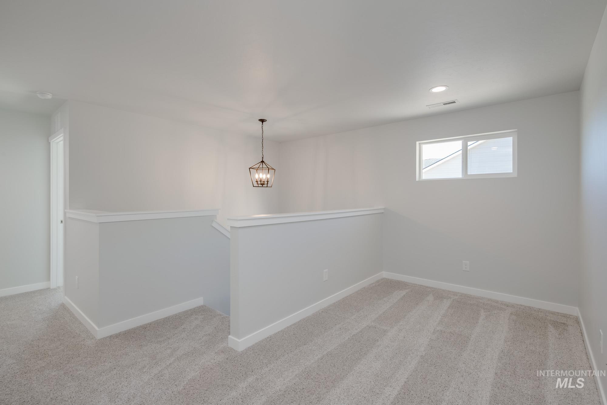 Spare room with light carpet, a chandelier, and recessed lighting