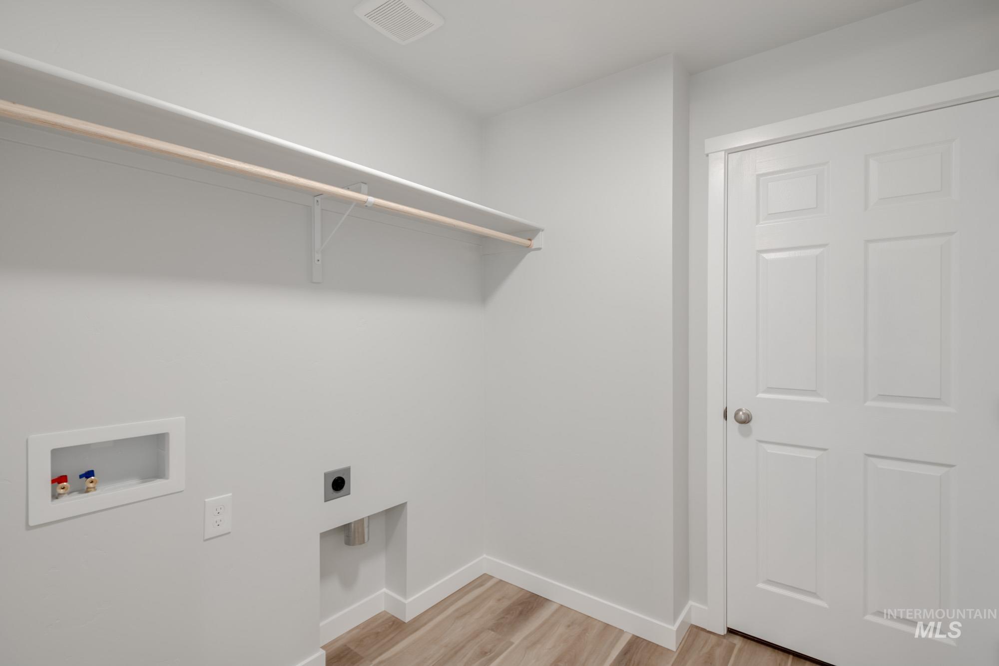 Washroom with light wood-type flooring, hookup for a washing machine, and hookup for an electric dryer