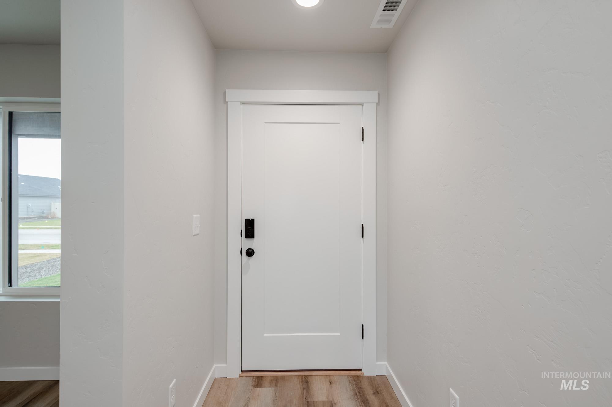 Doorway to outside with wood finished floors and baseboards