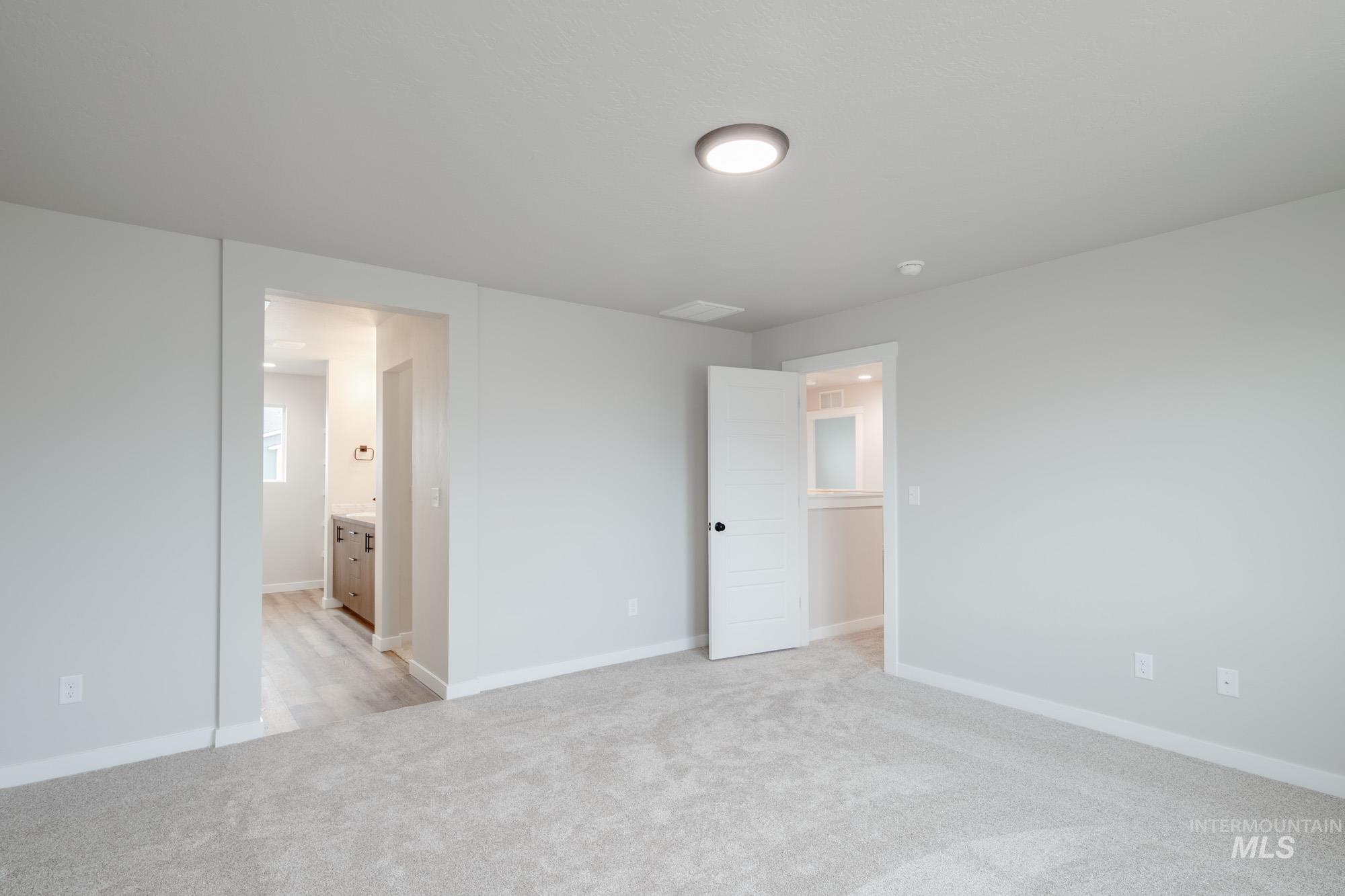 Unfurnished bedroom featuring light colored carpet and connected bathroom