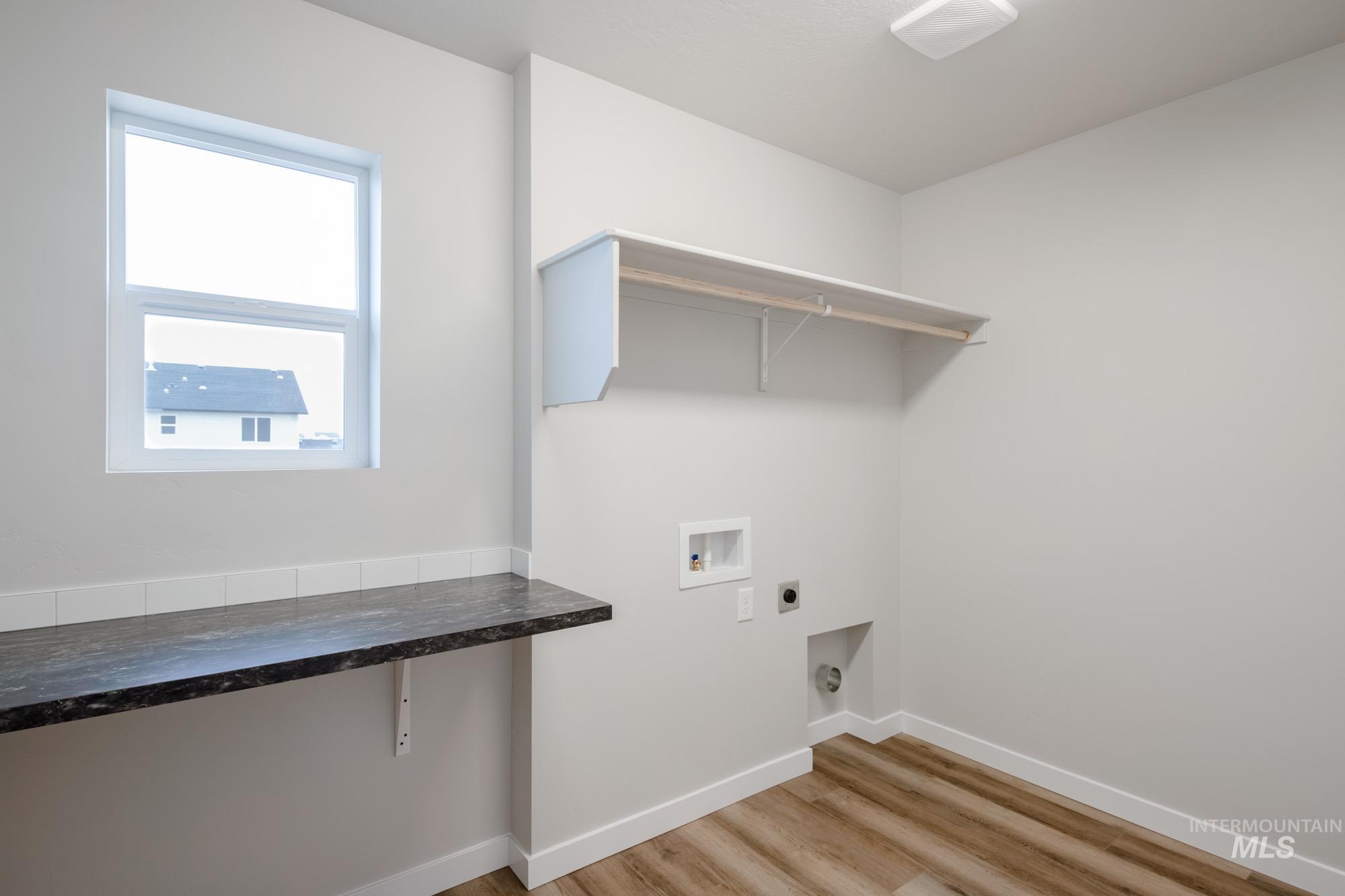 Laundry area with light wood-style floors, hookup for a washing machine, and electric dryer hookup