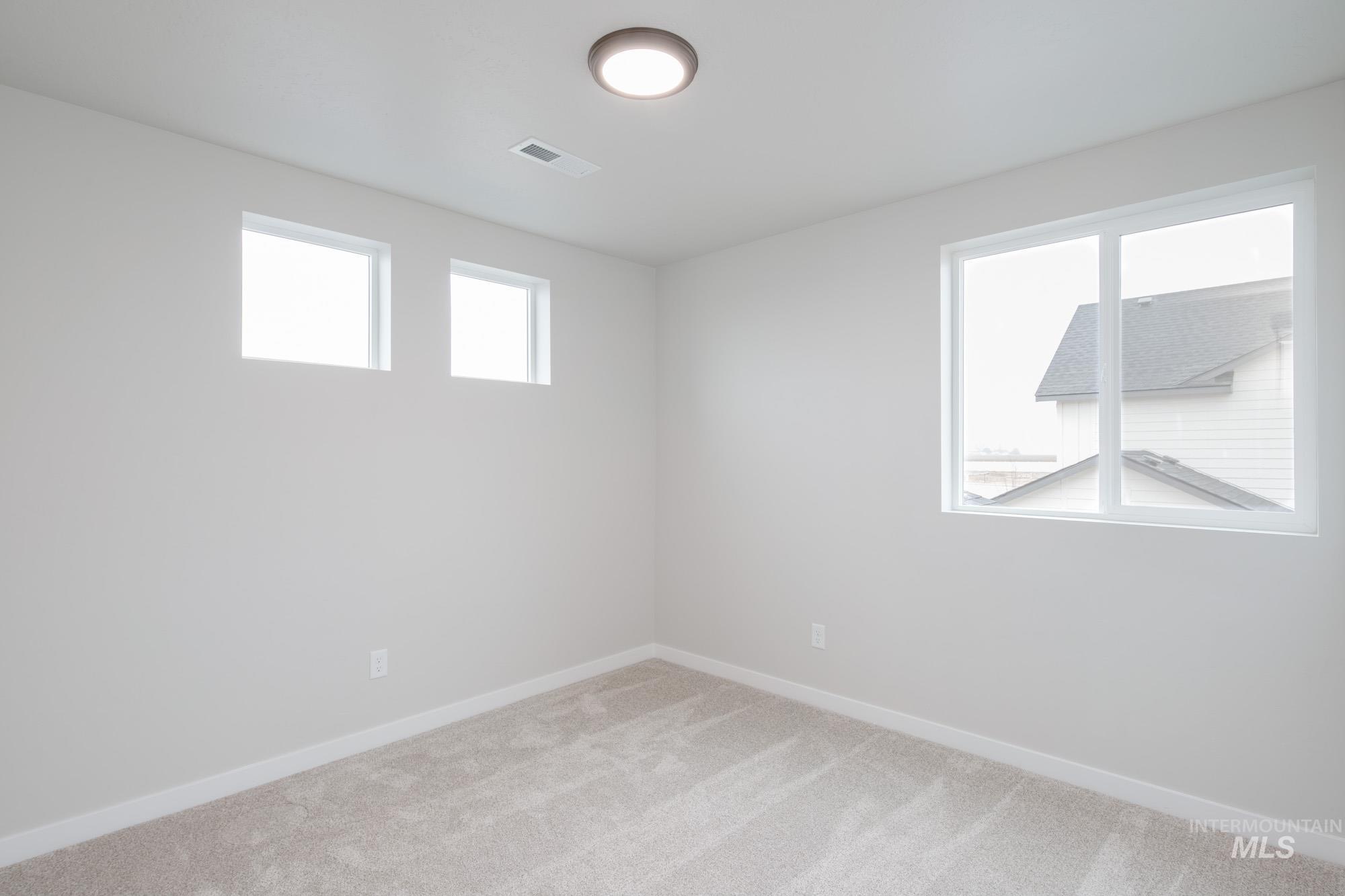 Empty room with light colored carpet and baseboards