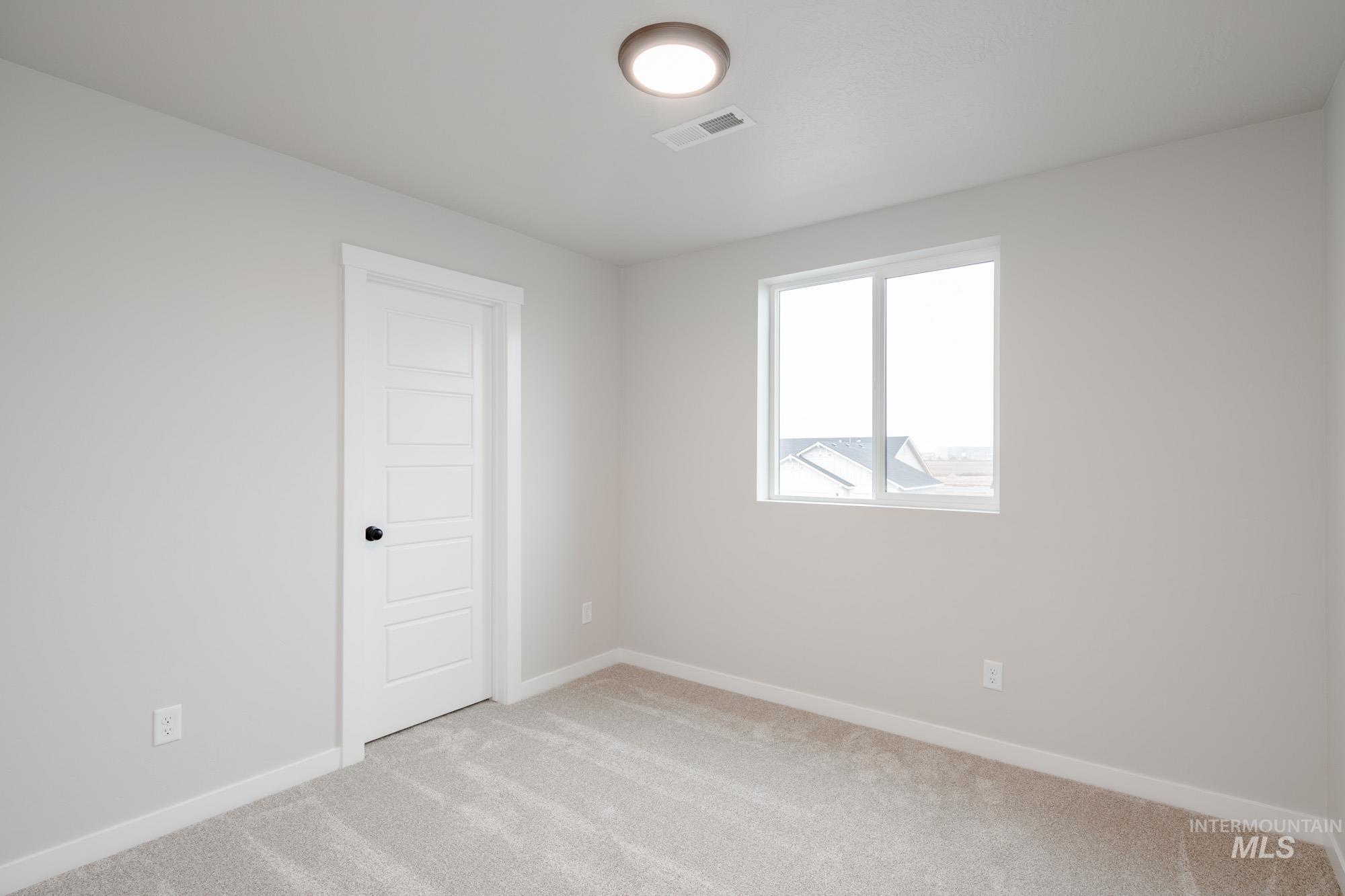 Spare room featuring light carpet and baseboards