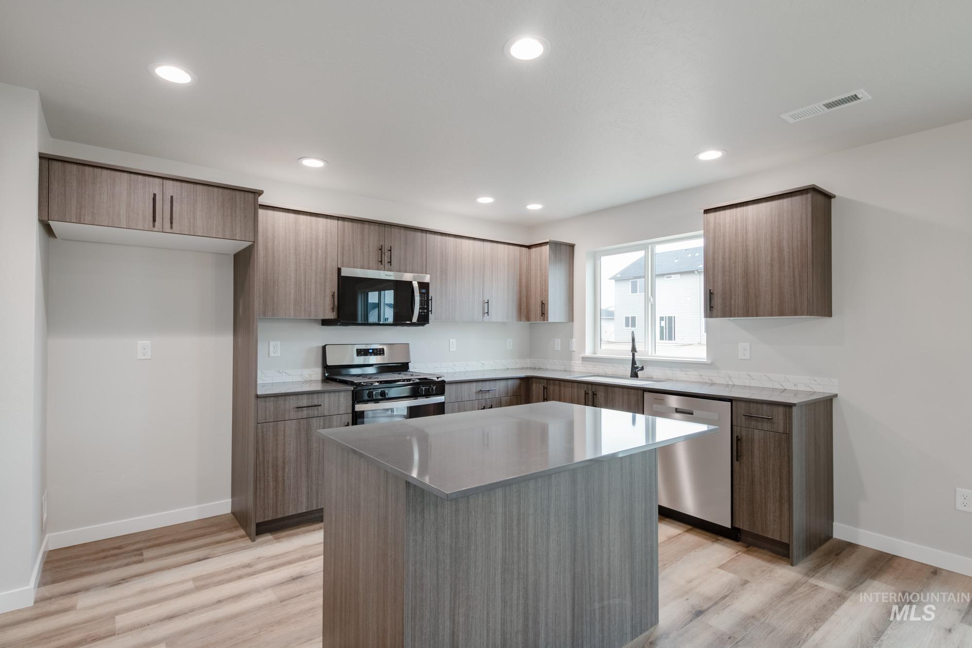 Kitchen featuring stainless steel appliances, a center island, light wood-type flooring, modern cabinets, and recessed lighting