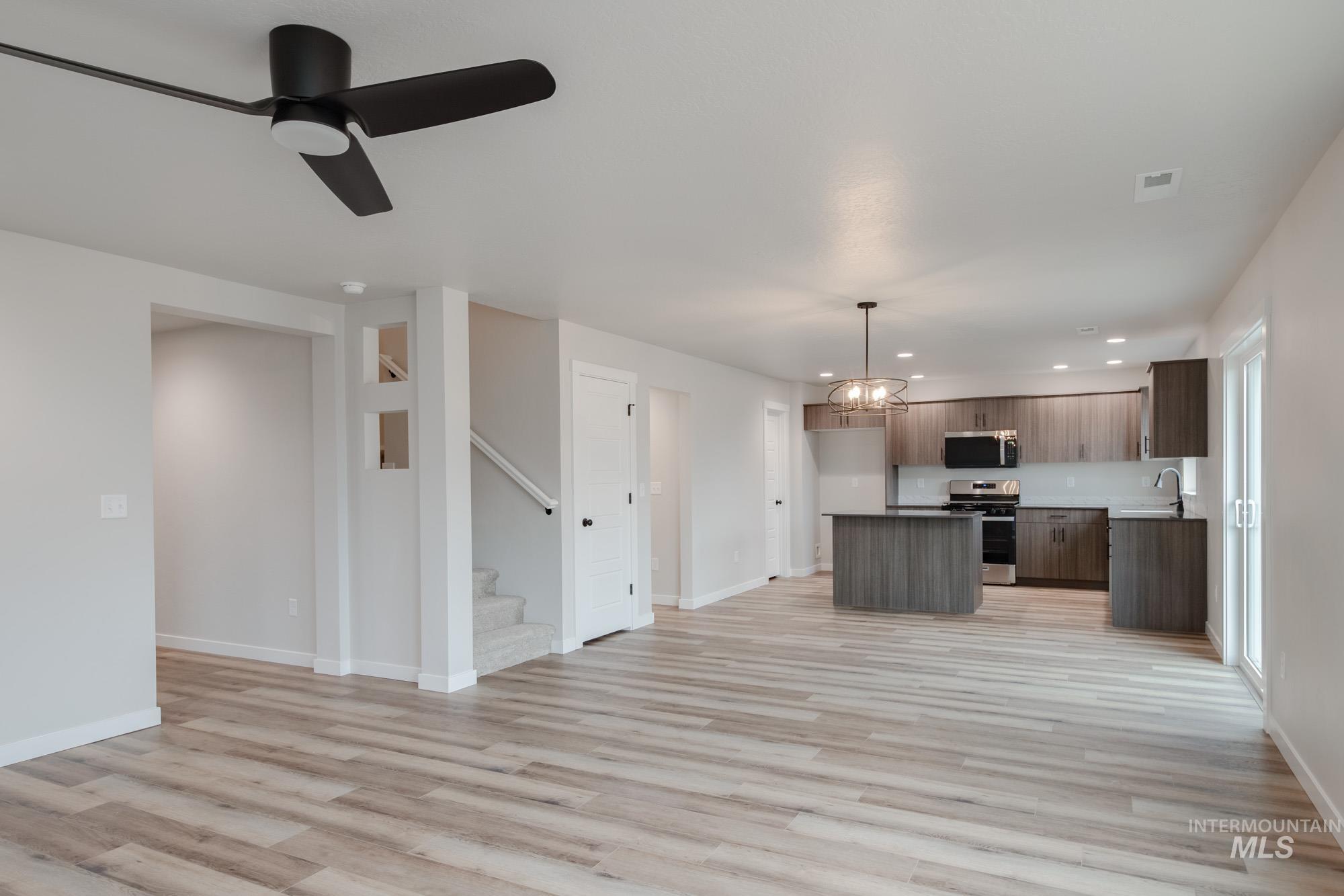 Kitchen featuring a chandelier, open floor plan, a kitchen island, appliances with stainless steel finishes, and pendant lighting