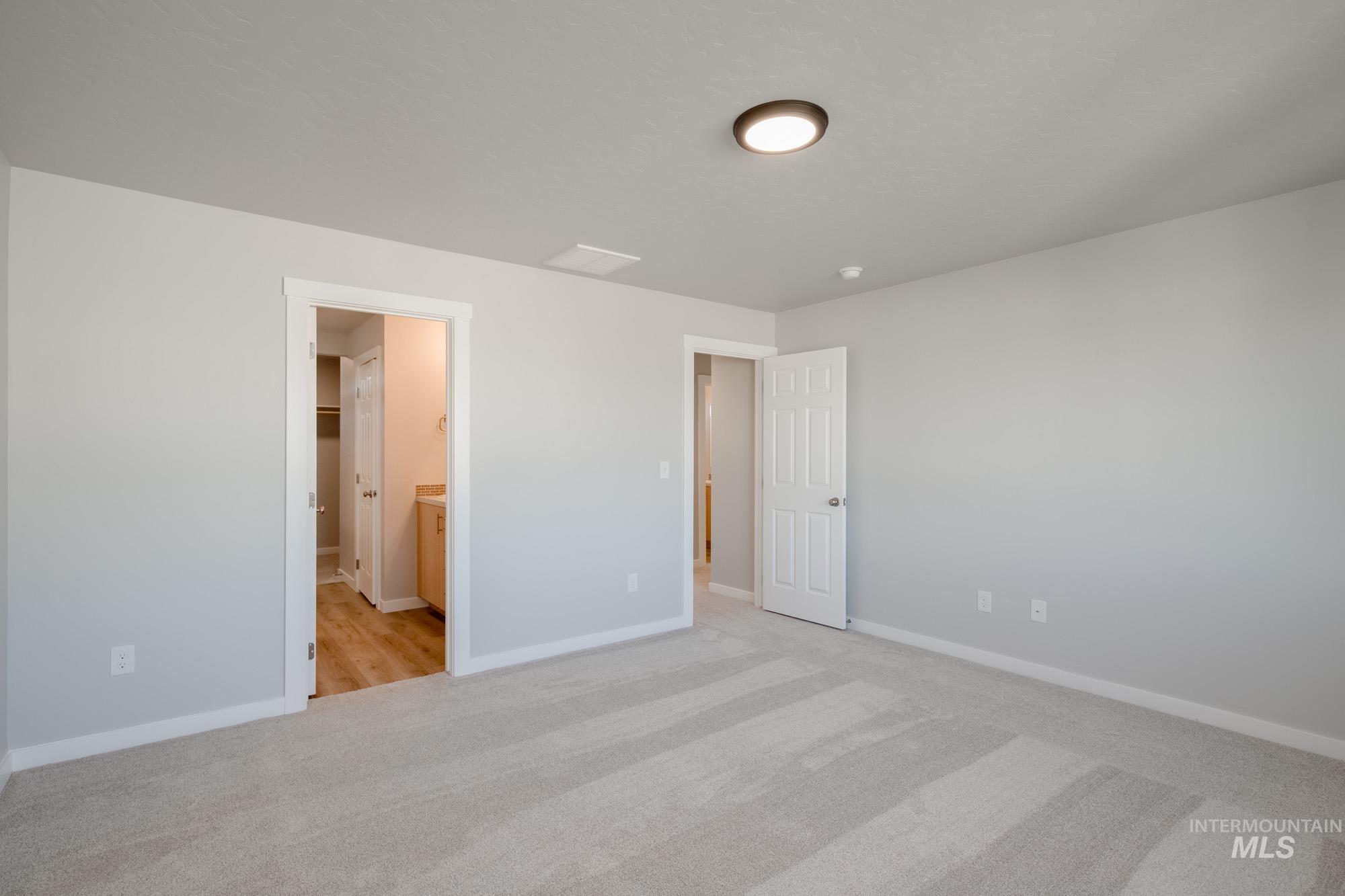 Unfurnished bedroom with light colored carpet and ensuite bath
