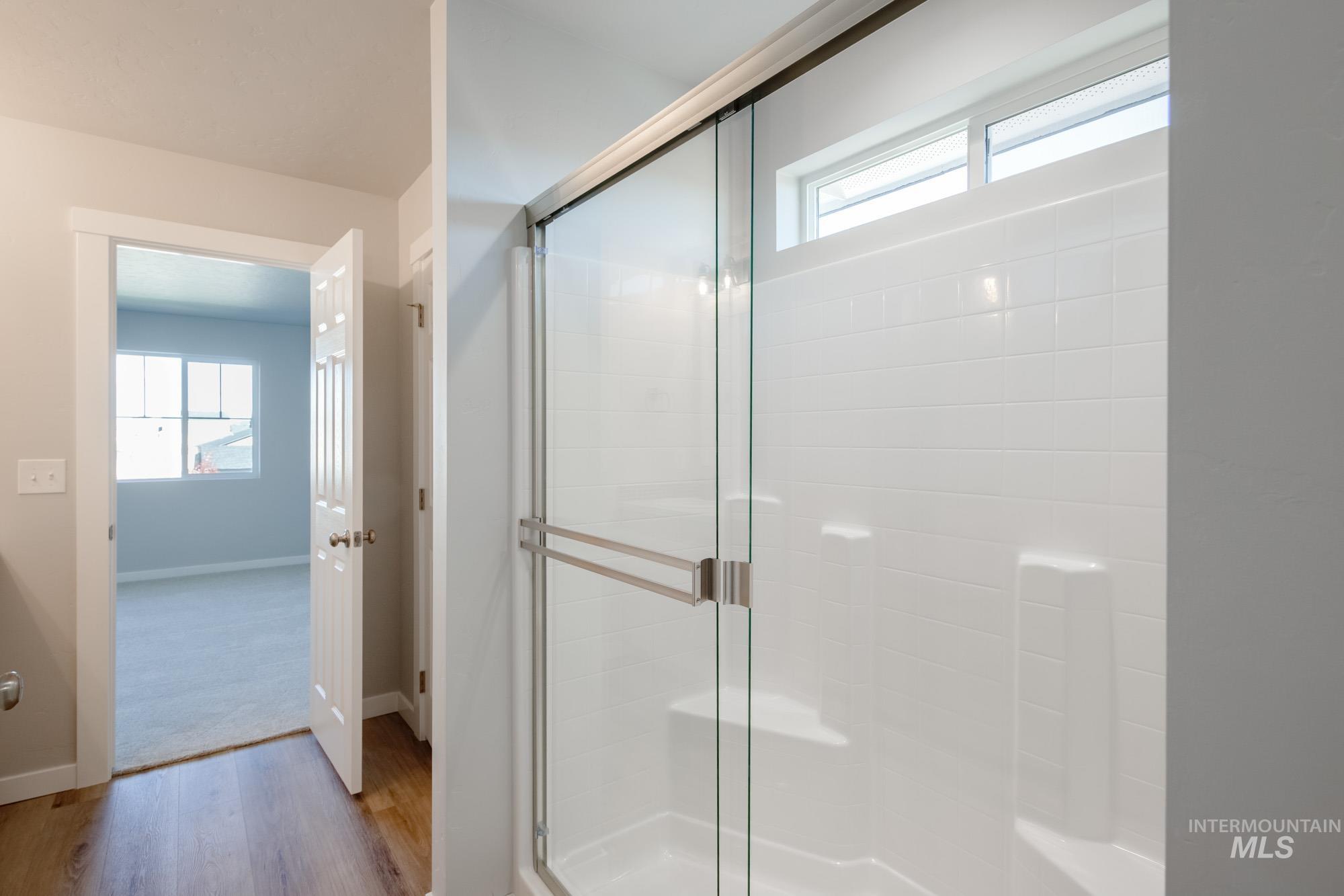 Full bathroom featuring healthy amount of natural light, light wood-style flooring, and a shower stall