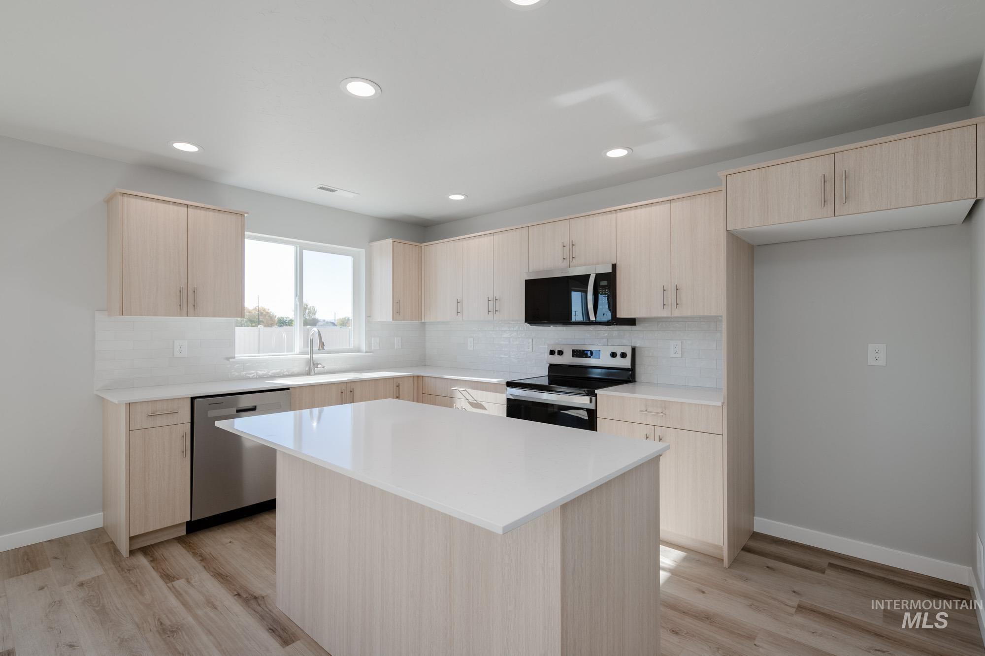 Kitchen with light brown cabinetry, backsplash, stainless steel appliances, recessed lighting, and light wood-type flooring