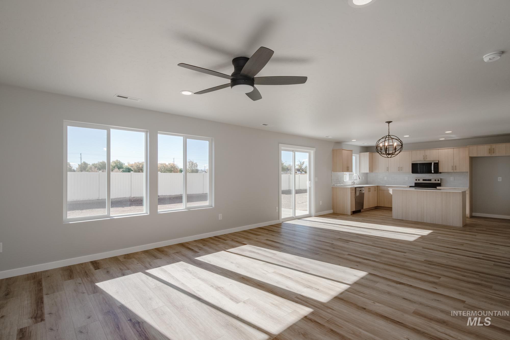 Unfurnished living room with a chandelier, light wood-style floors, recessed lighting, and ceiling fan