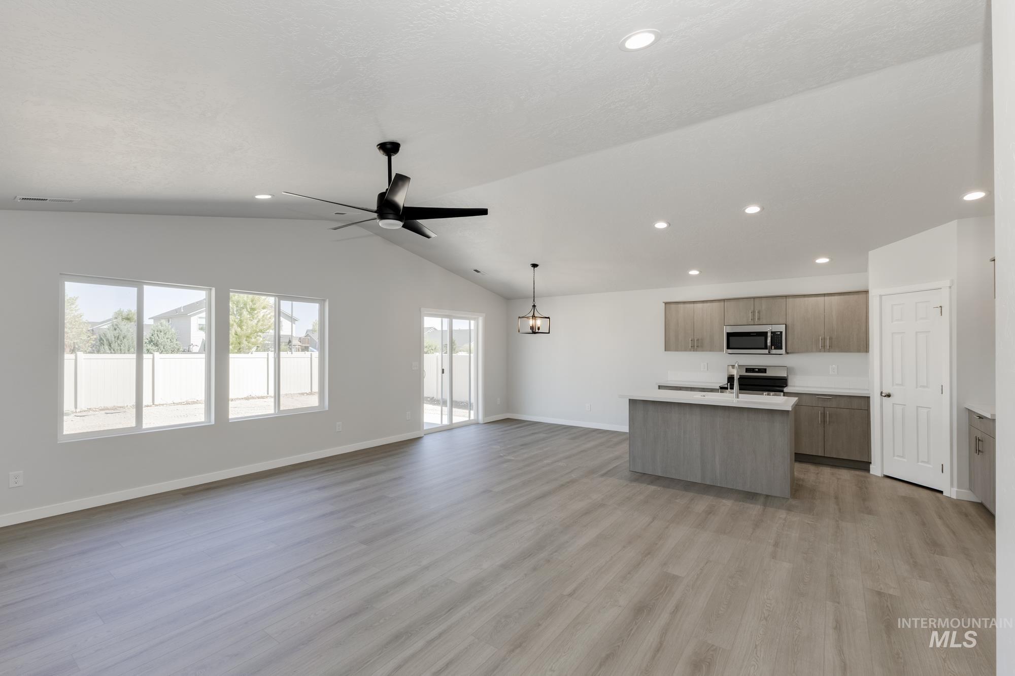 Kitchen with open floor plan, a center island with sink, light countertops, light wood finished floors, and recessed lighting