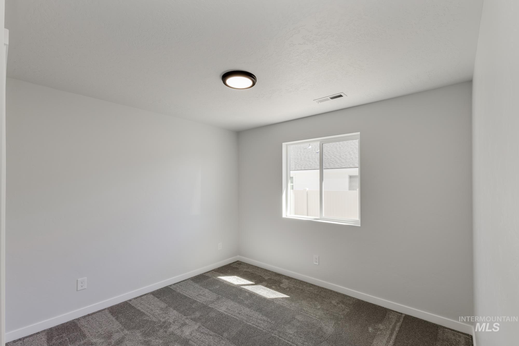 Spare room with dark colored carpet and baseboards