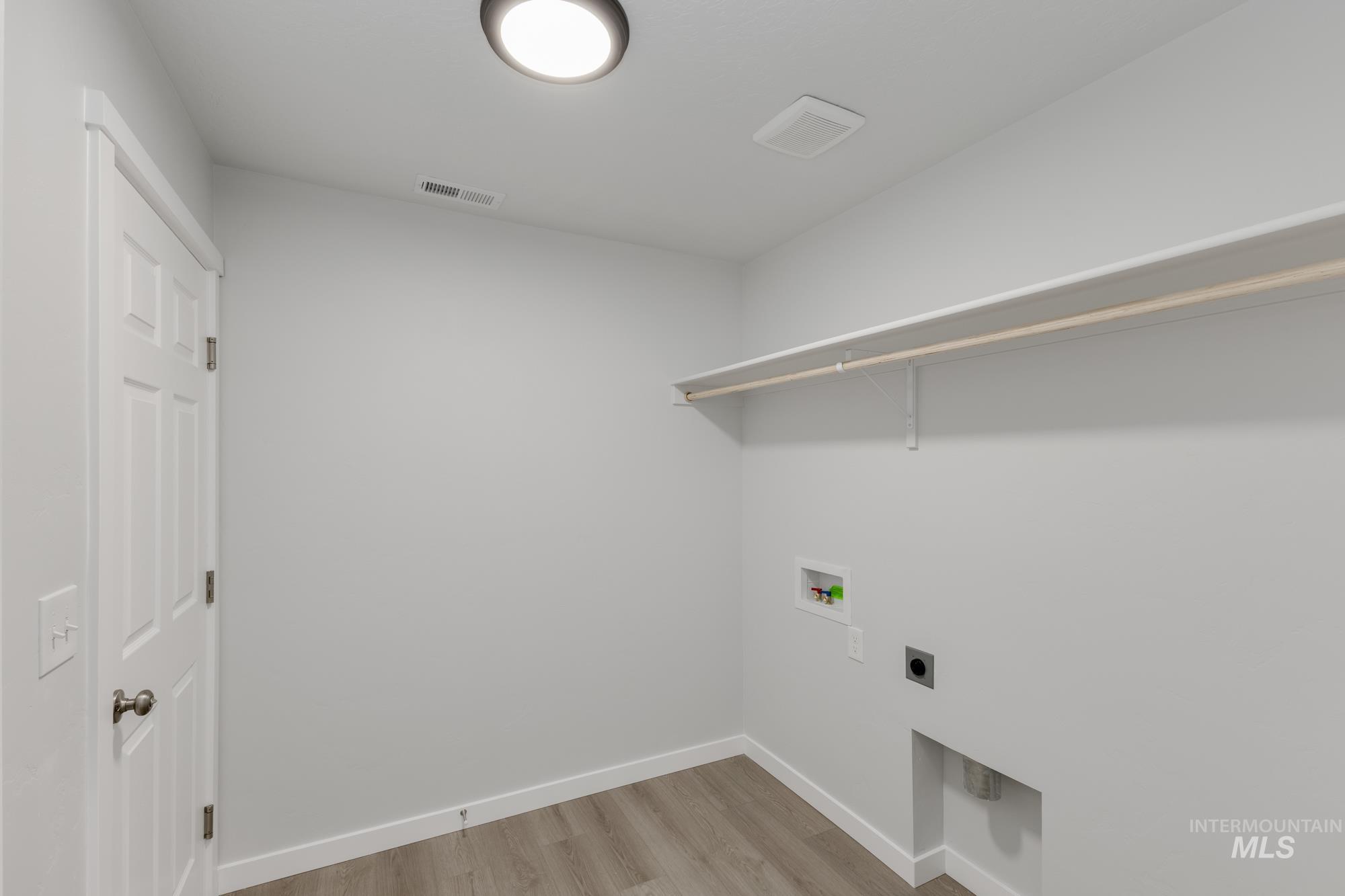 Laundry room with light wood-type flooring, hookup for a washing machine, and hookup for an electric dryer