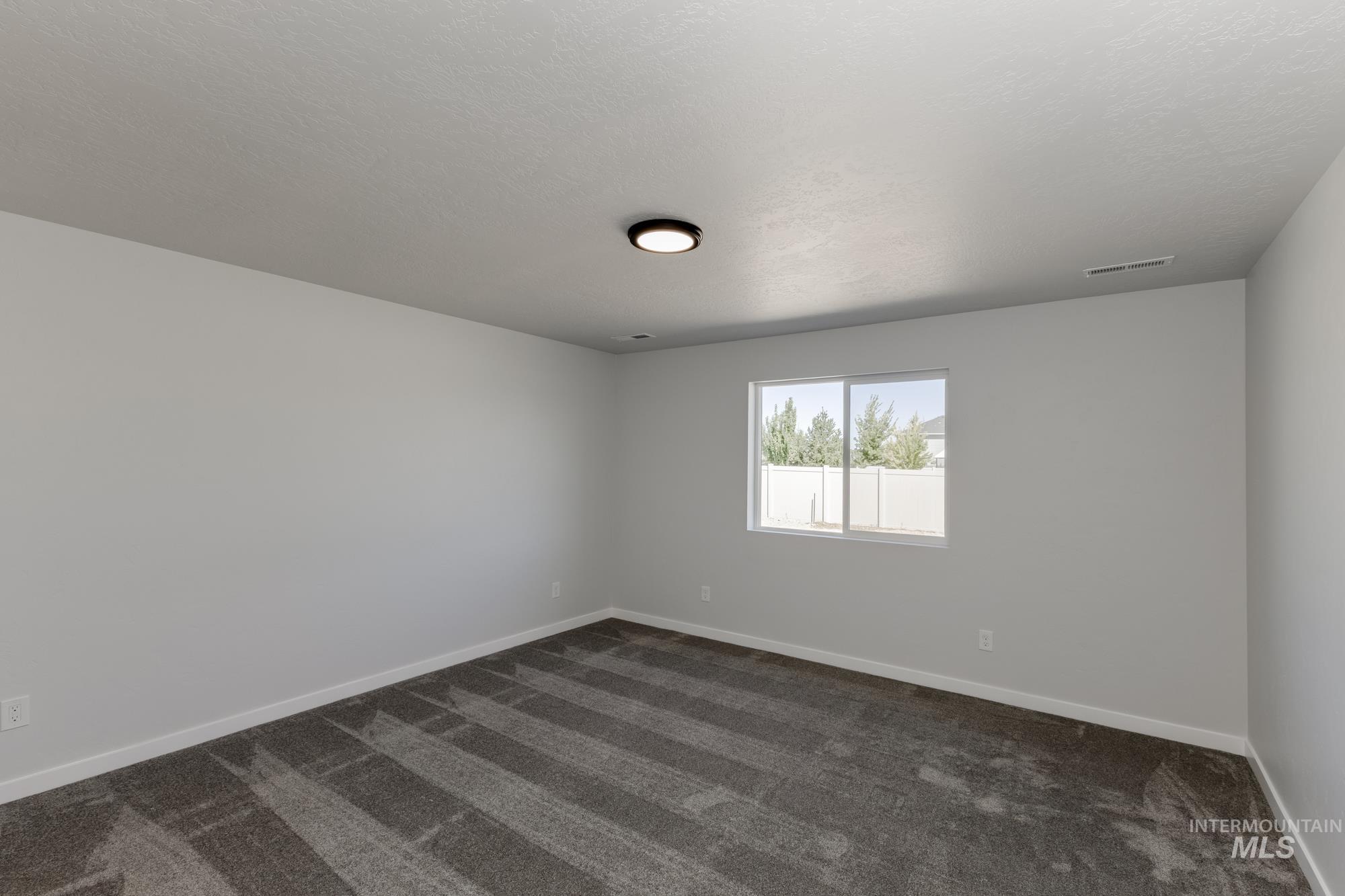 Spare room with dark carpet and a textured ceiling