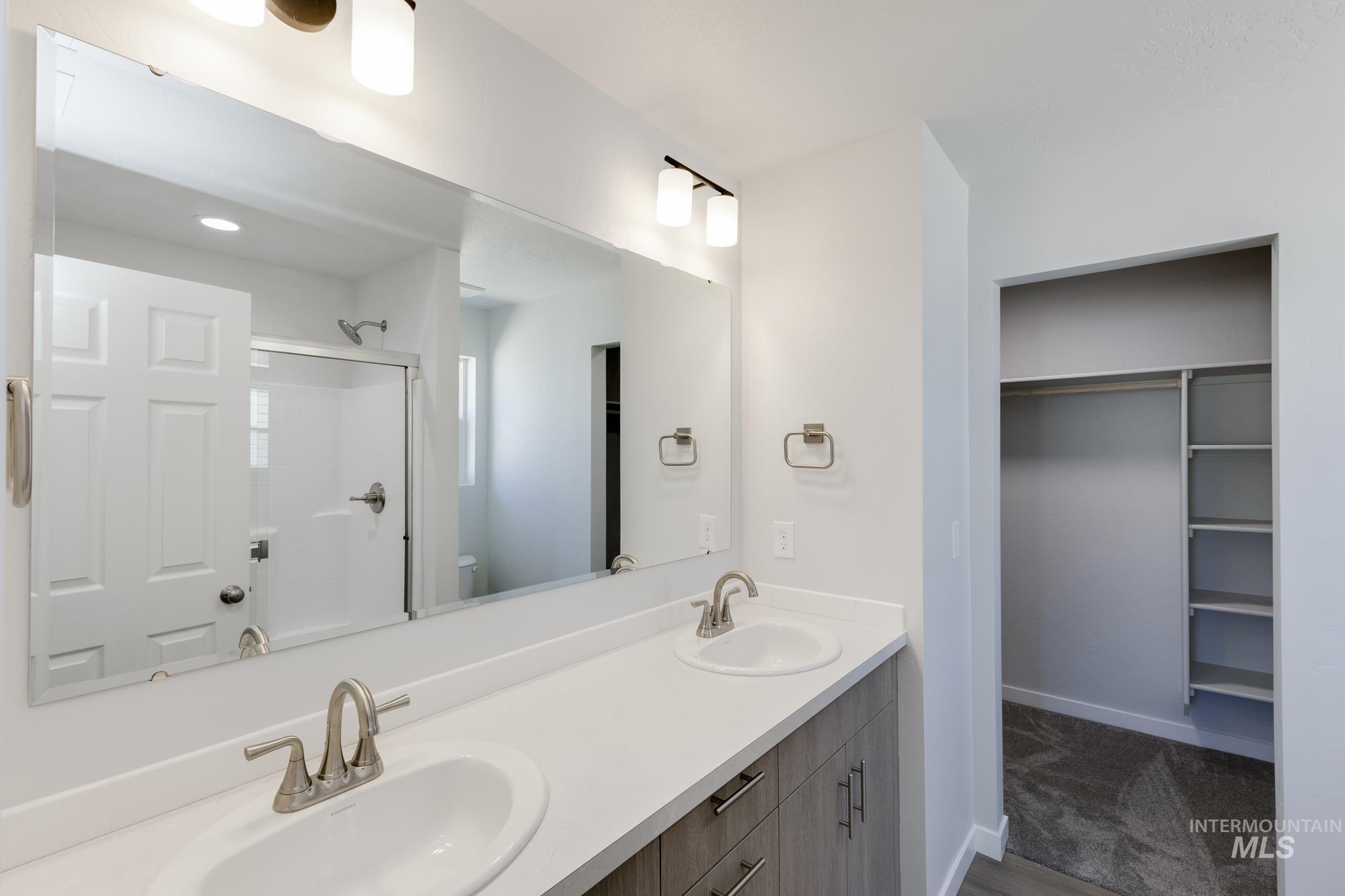 Bathroom featuring double vanity, a walk in closet, and a shower stall