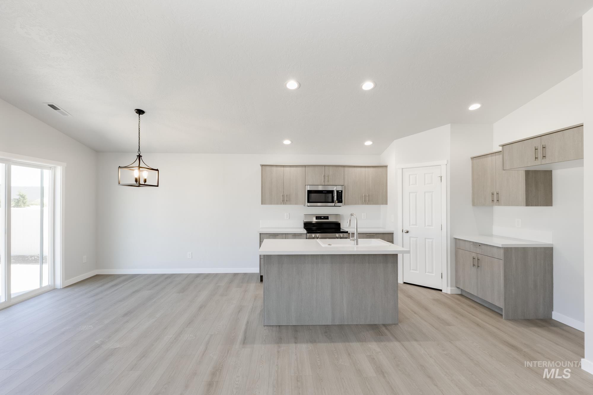 Kitchen featuring an island with sink, modern cabinets, hanging light fixtures, light wood finished floors, and recessed lighting