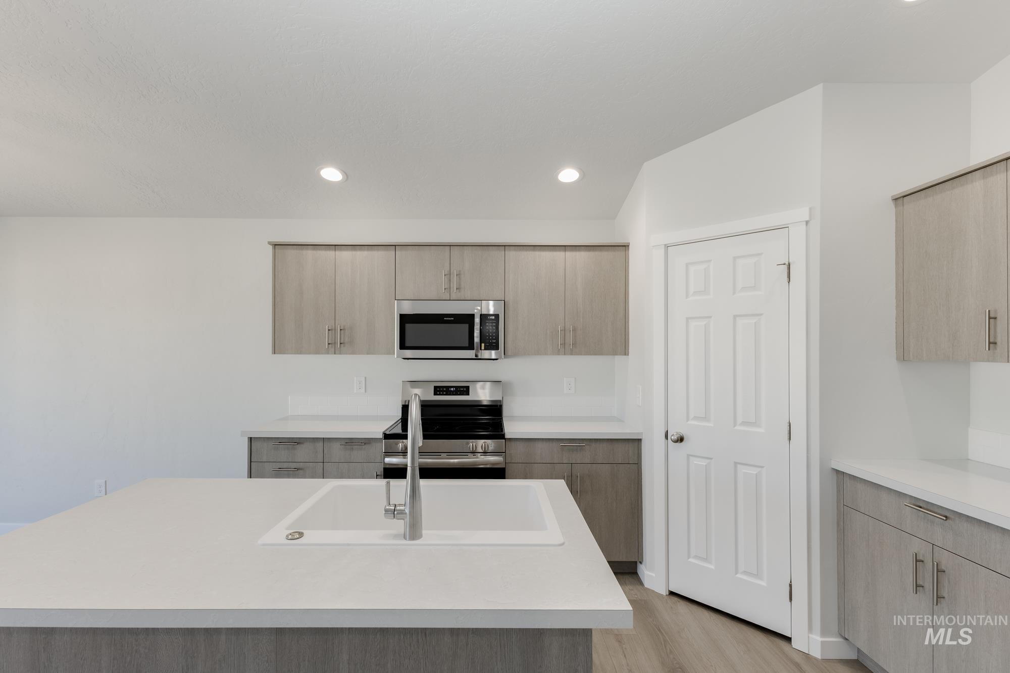 Kitchen featuring light brown cabinets, appliances with stainless steel finishes, light wood-style floors, recessed lighting, and modern cabinets