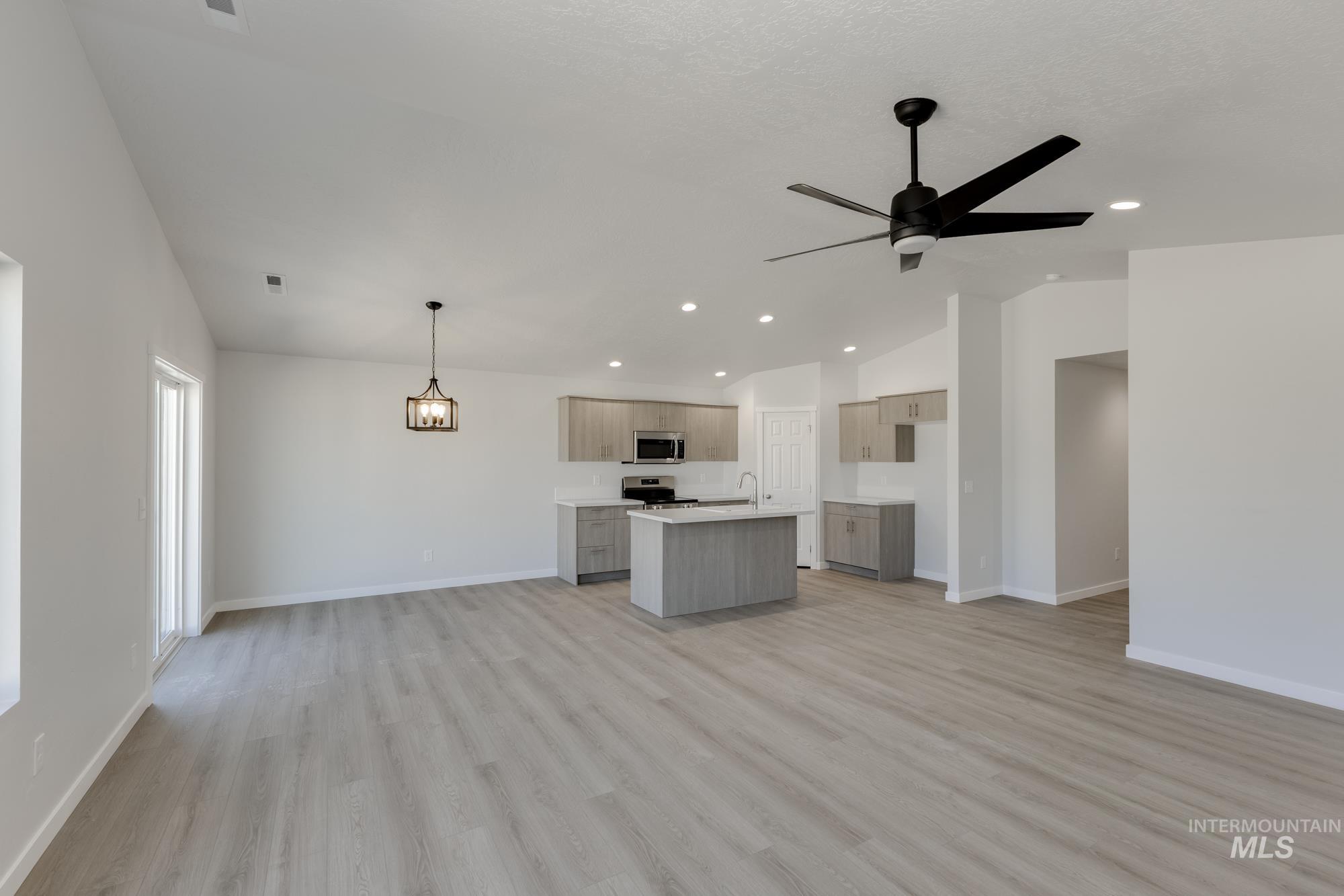 Unfurnished living room featuring vaulted ceiling, light wood-style floors, a ceiling fan, and recessed lighting