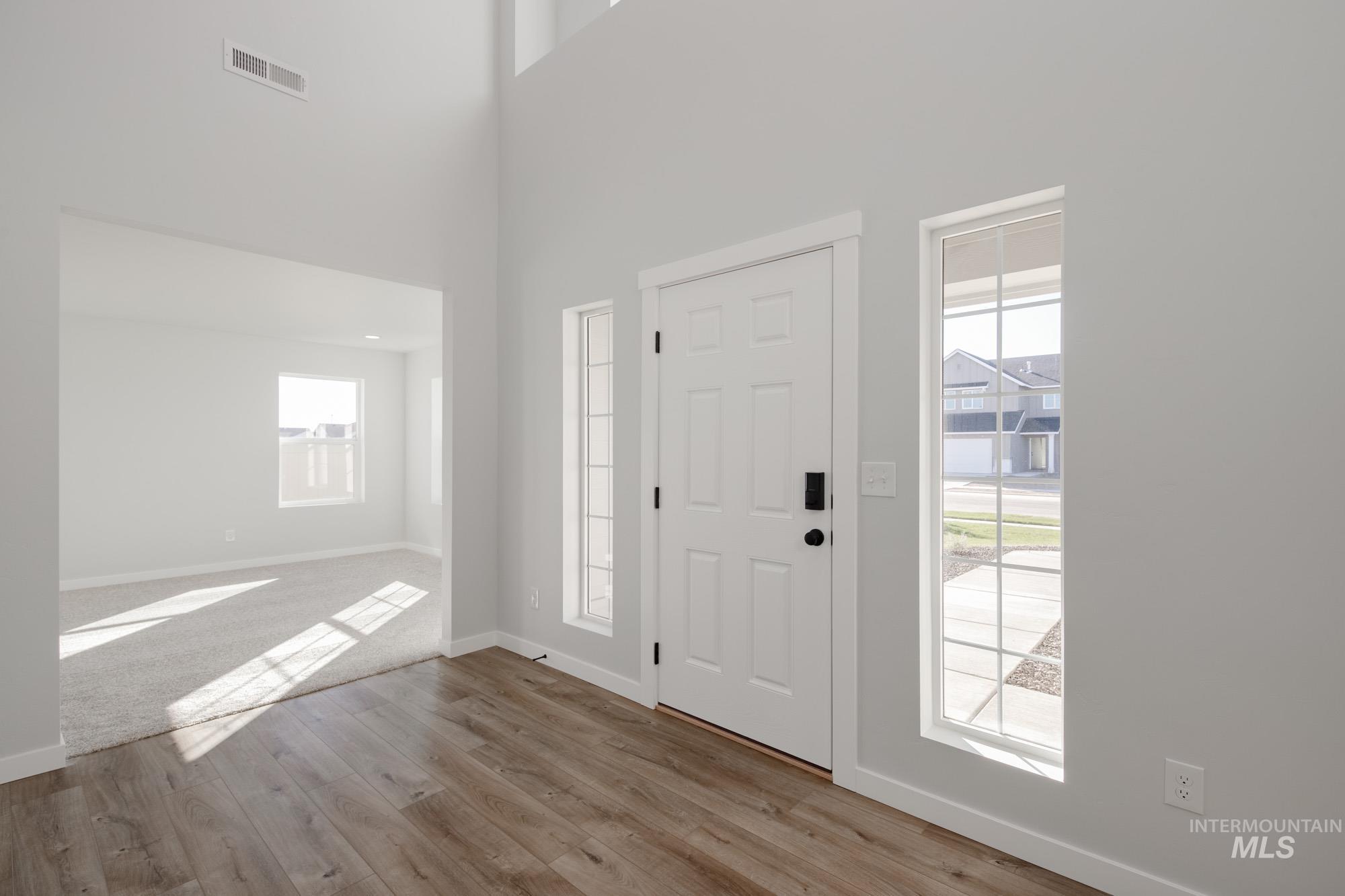 Entrance foyer featuring light wood-style flooring and a towering ceiling