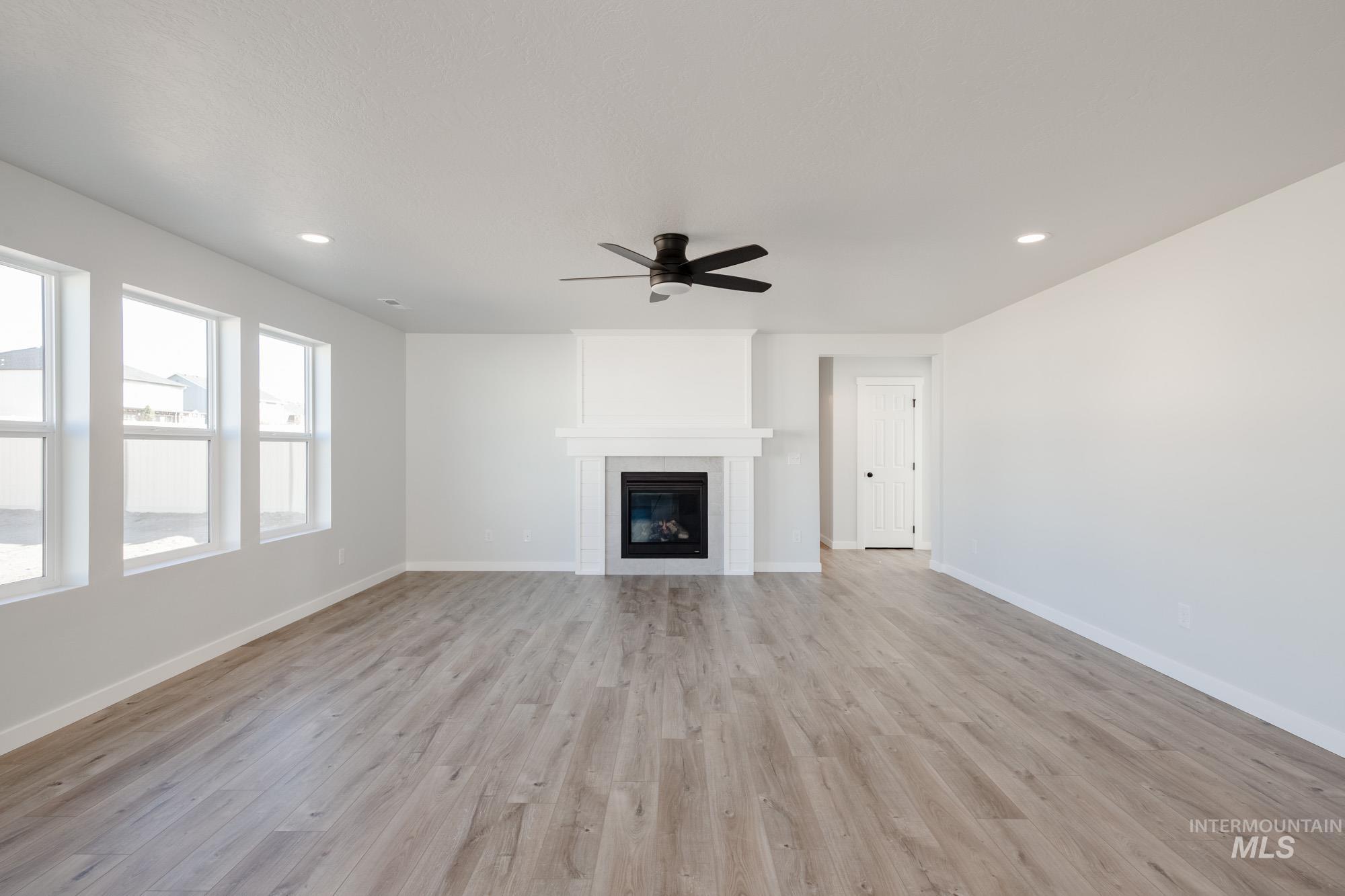 Unfurnished living room featuring light wood-style floors, recessed lighting, a fireplace, and a ceiling fan
