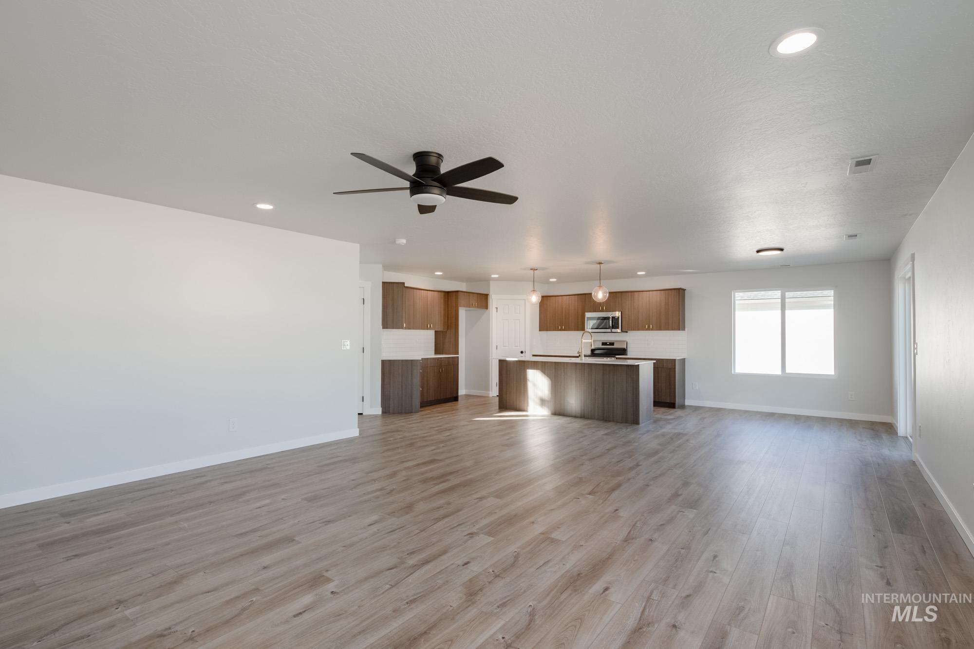 Unfurnished living room with light wood finished floors, recessed lighting, and a ceiling fan