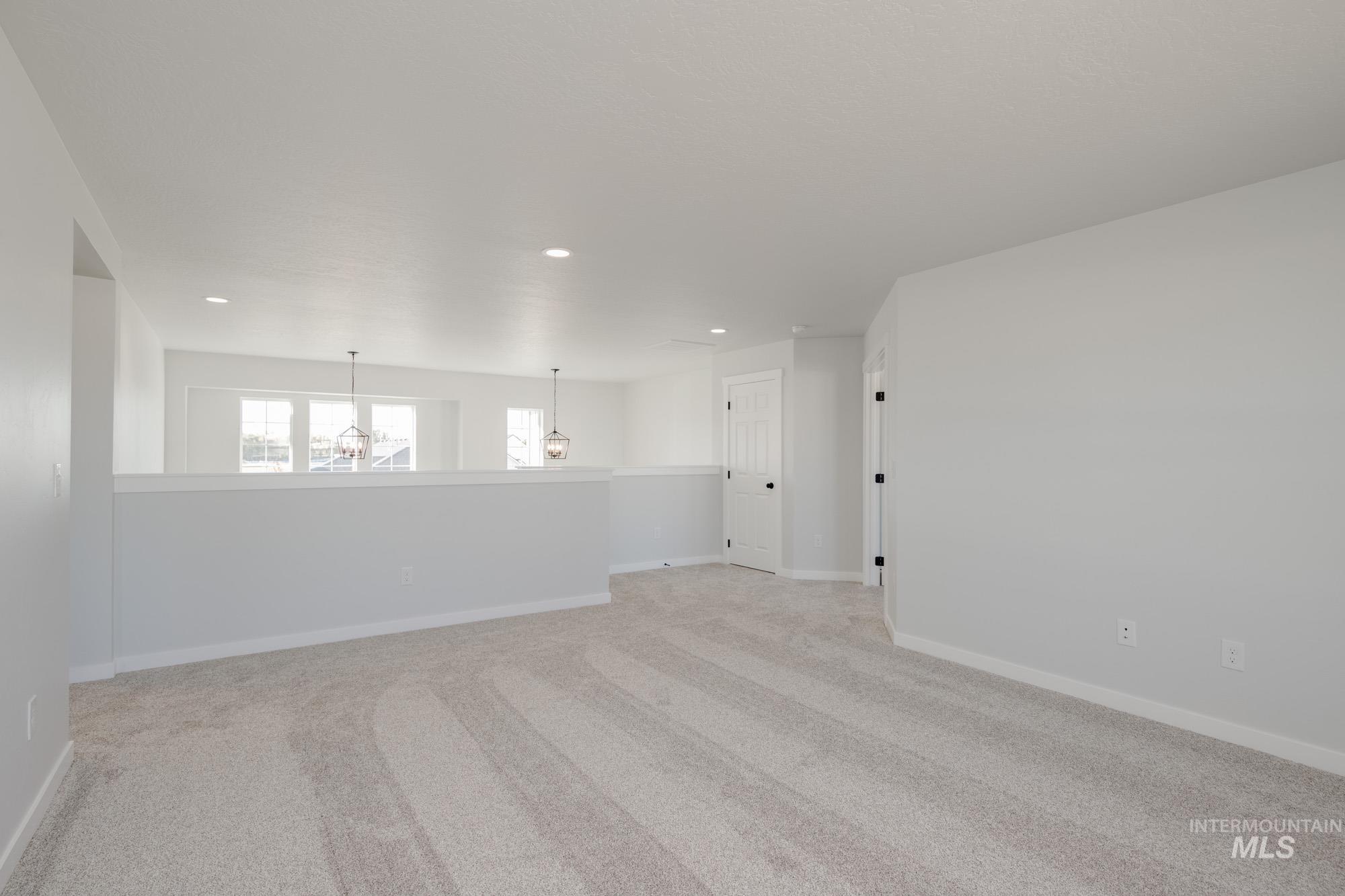 Spare room featuring light carpet, recessed lighting, and a chandelier