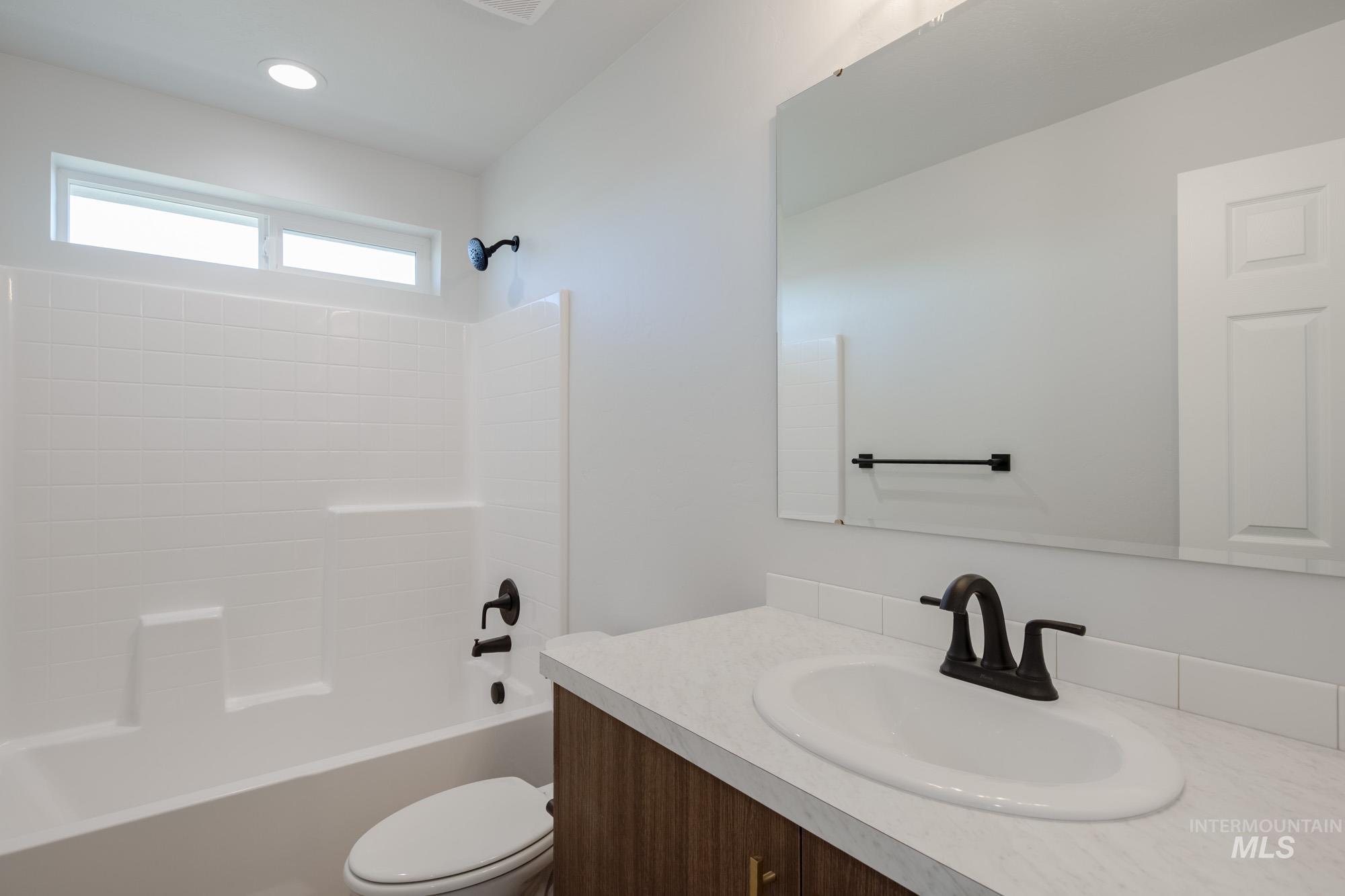 Bathroom featuring washtub / shower combination, vanity, and recessed lighting