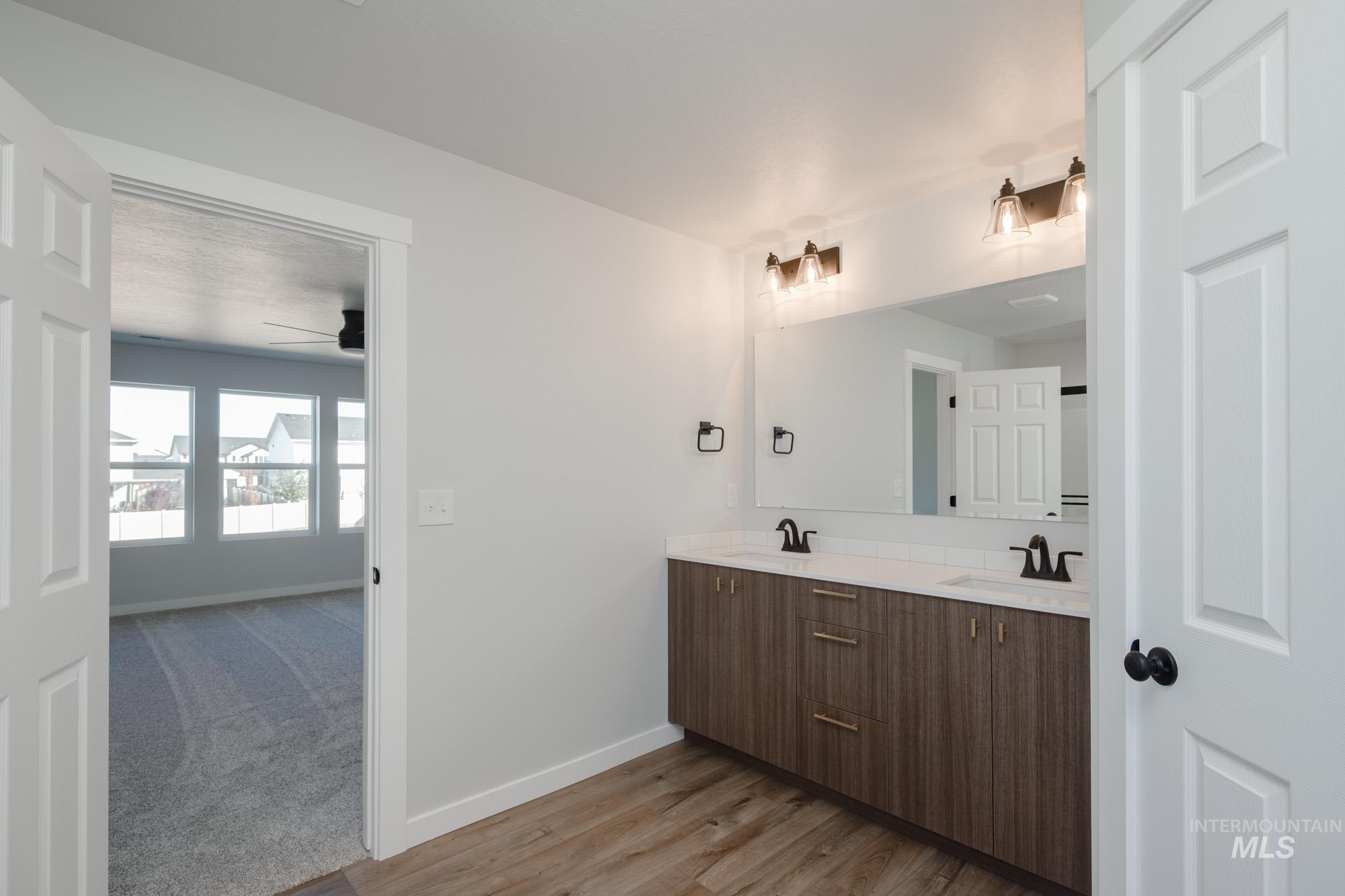 Bathroom featuring double vanity, light wood finished floors, a ceiling fan, and light carpet