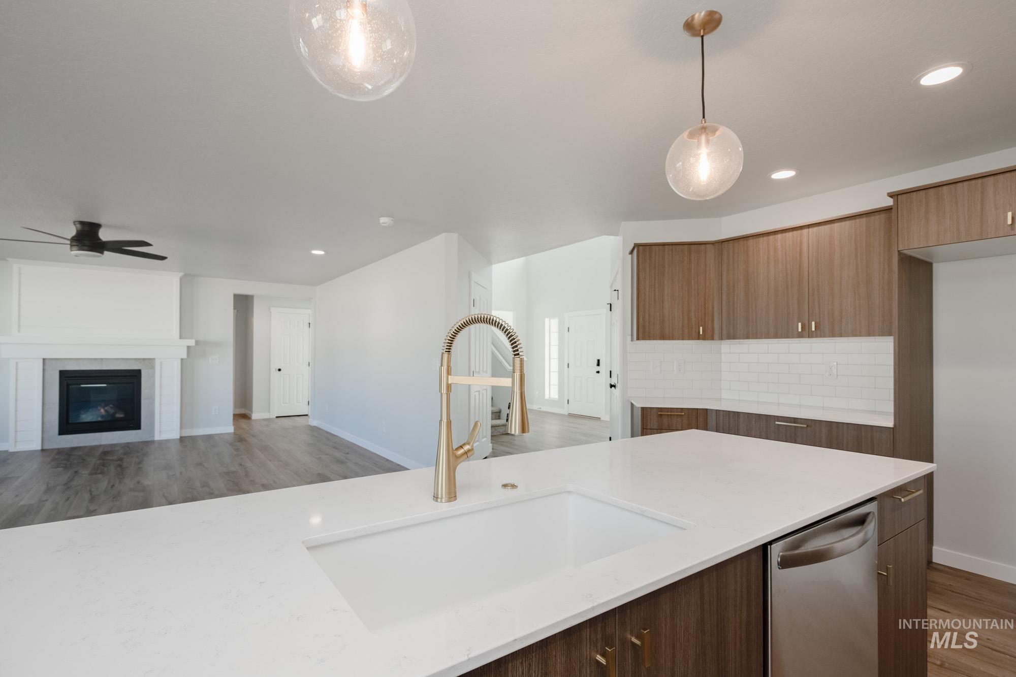 Kitchen with light wood-style flooring, open floor plan, decorative light fixtures, light stone countertops, and decorative backsplash