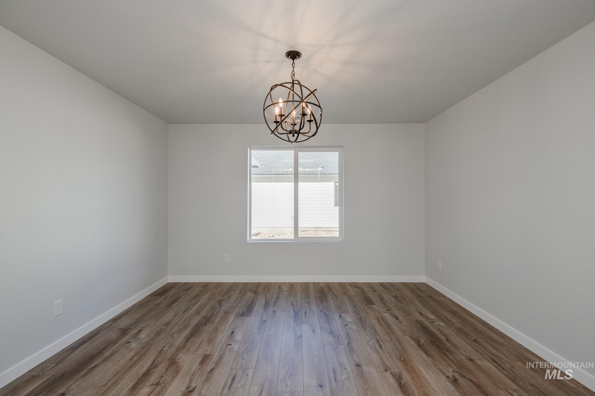 Unfurnished room with wood finished floors and a chandelier