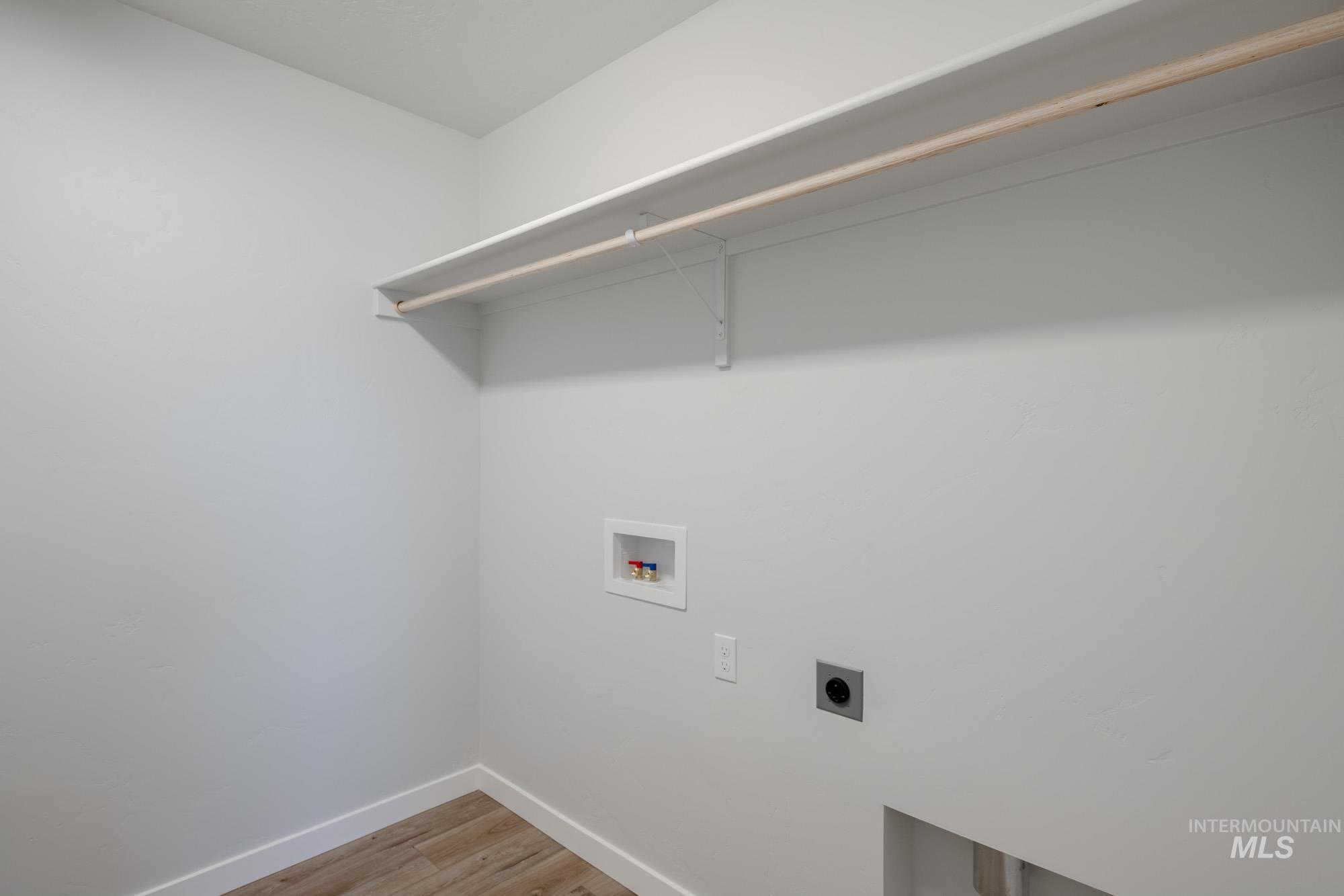 Laundry area with electric dryer hookup, hookup for a washing machine, and light wood-style flooring