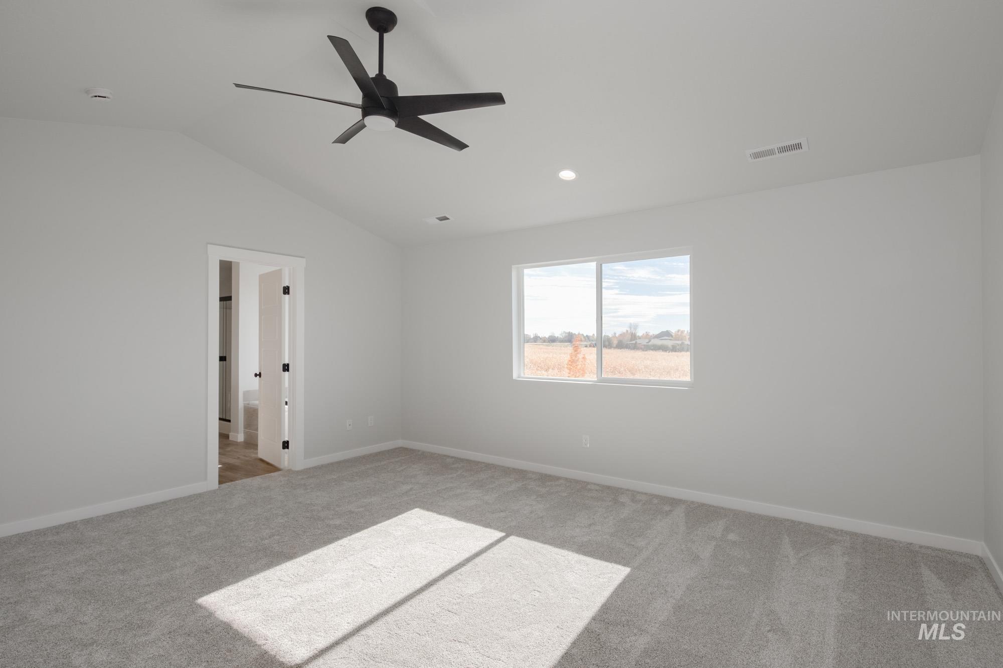 Empty room with light carpet, ceiling fan, vaulted ceiling, and recessed lighting