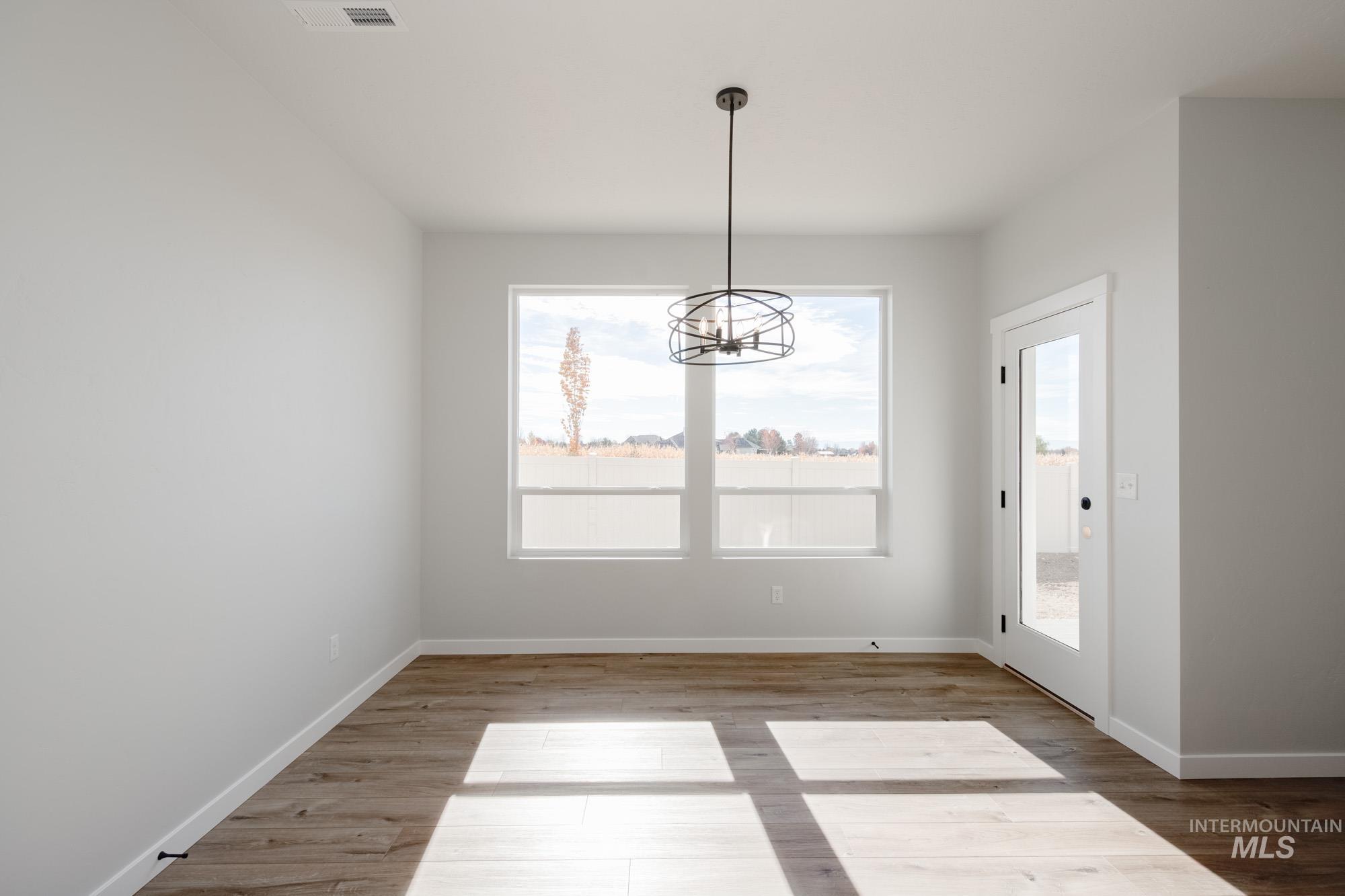 Unfurnished dining area with a chandelier and light wood-style flooring