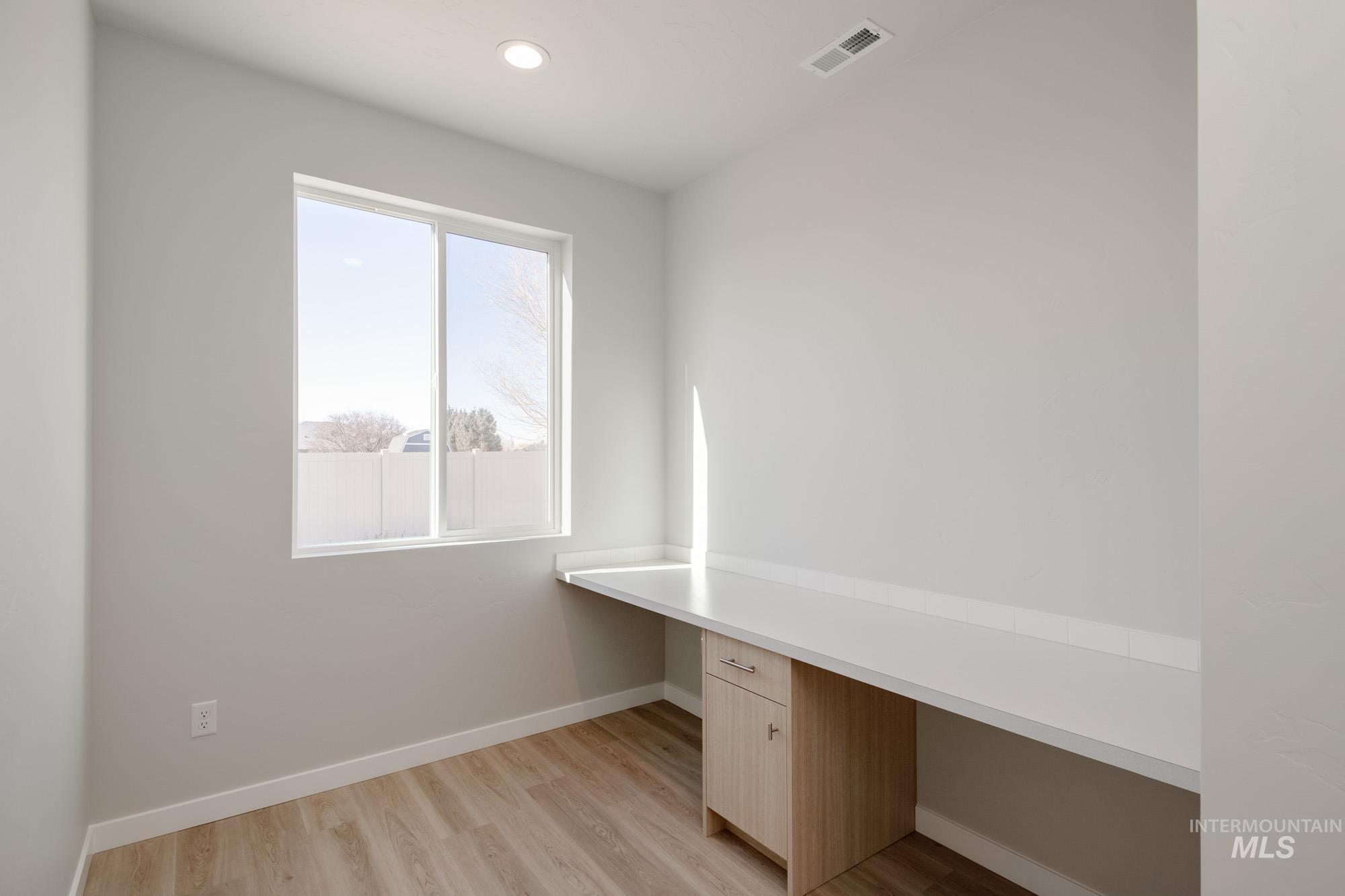 Unfurnished office featuring built in desk, light wood-type flooring, and recessed lighting