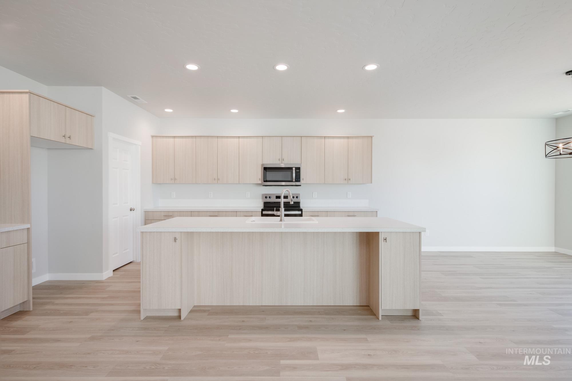 Kitchen with light brown cabinetry, modern cabinets, a kitchen island with sink, light wood finished floors, and recessed lighting
