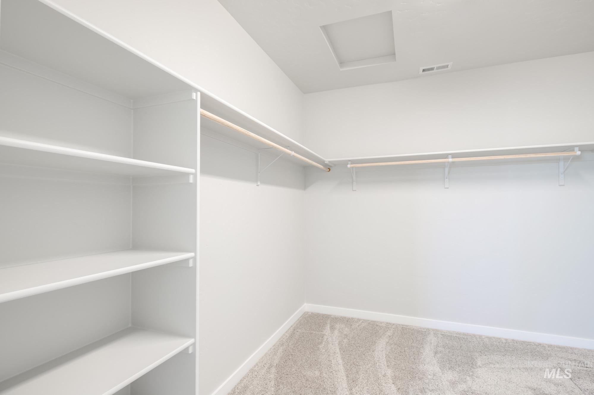 Walk in closet with attic access and light carpet