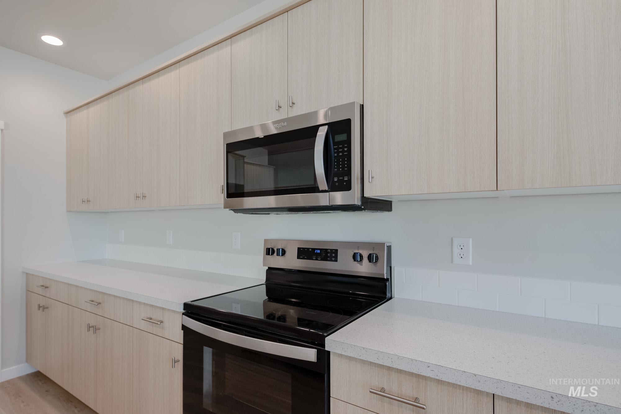 Kitchen with light brown cabinets, appliances with stainless steel finishes, light countertops, modern cabinets, and recessed lighting