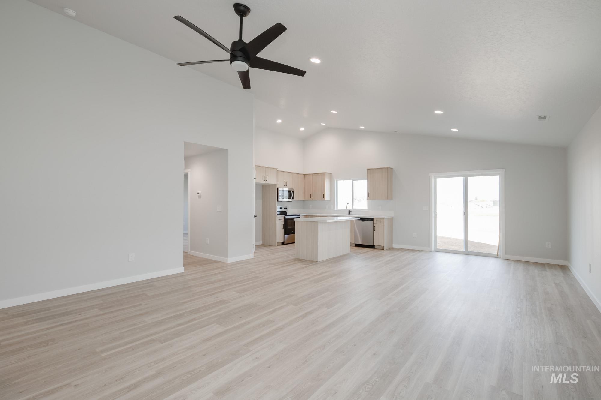 Unfurnished living room featuring light wood finished floors, a ceiling fan, recessed lighting, and high vaulted ceiling
