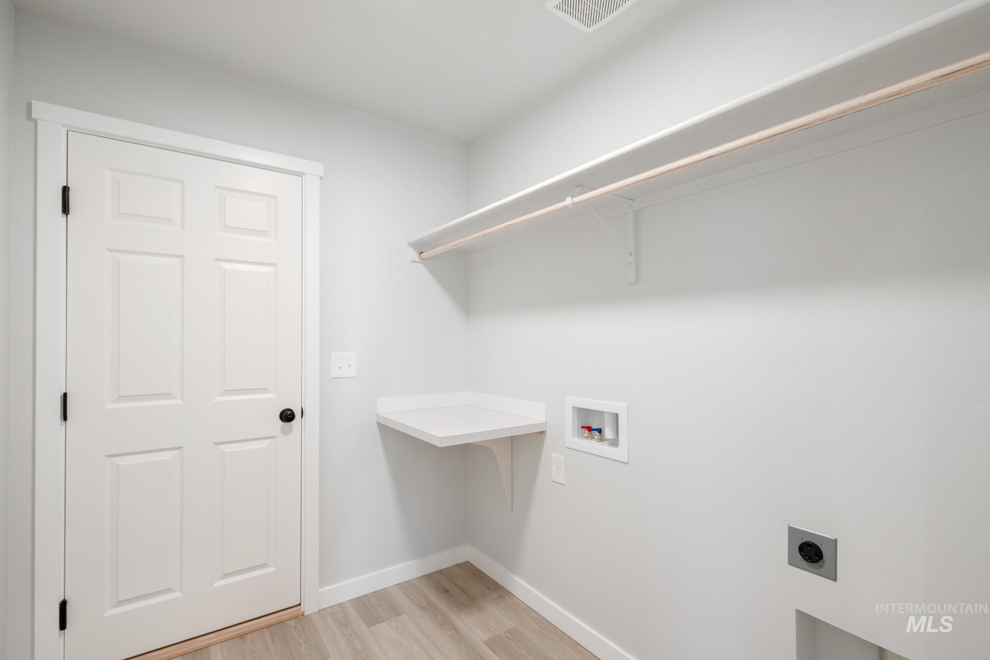 Laundry area featuring light wood-type flooring, washer hookup, and hookup for an electric dryer