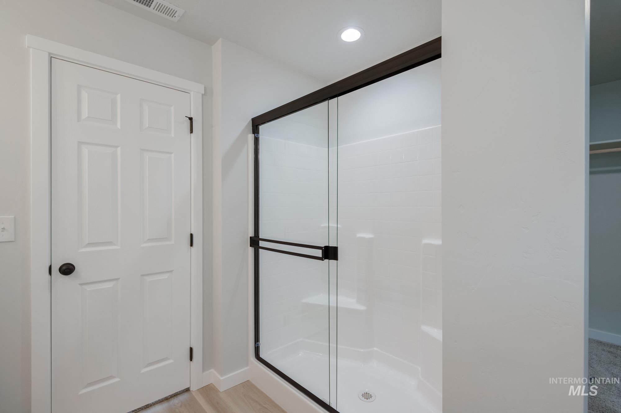 Bathroom featuring a stall shower, light wood finished floors, and recessed lighting