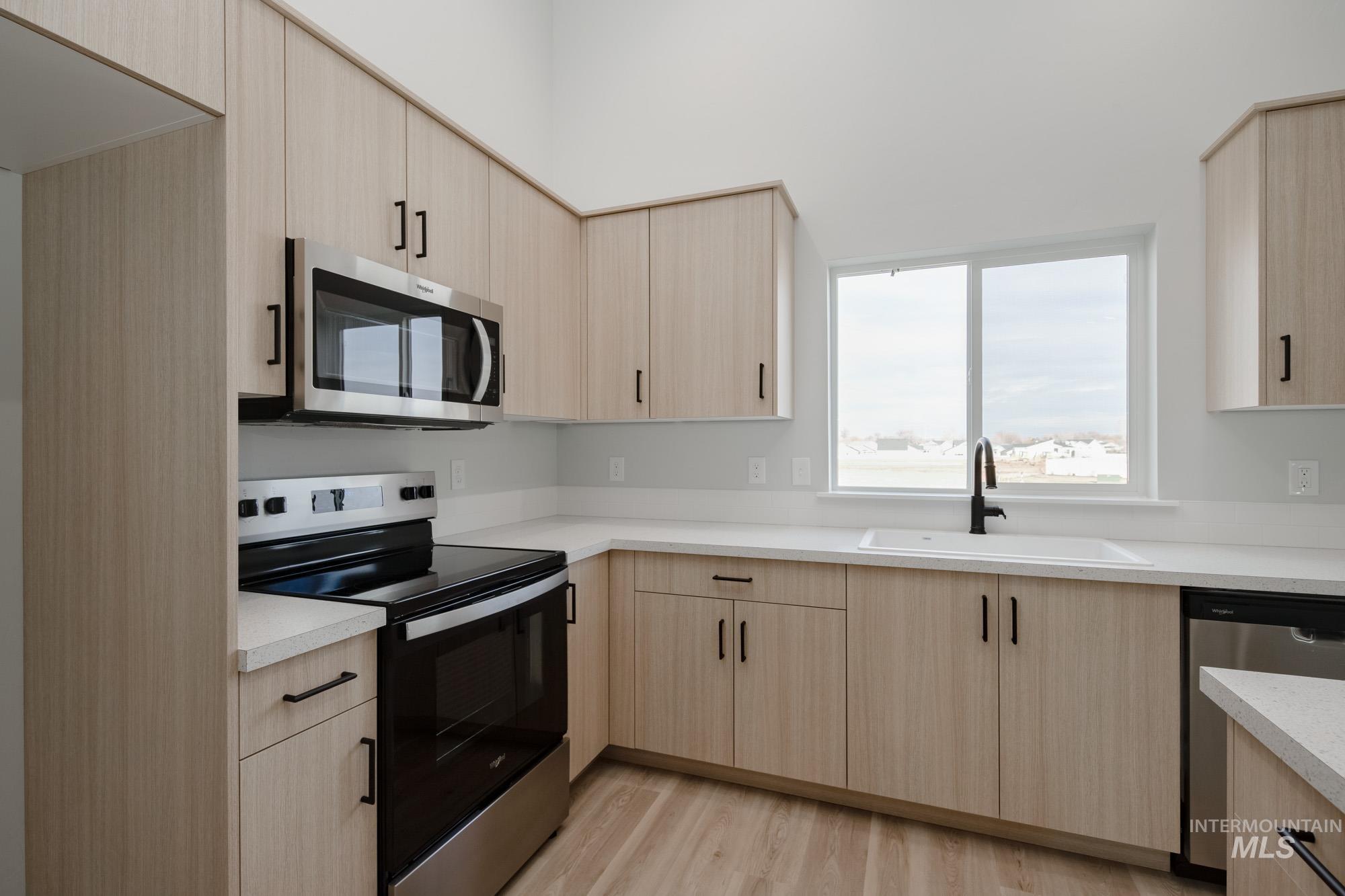 Kitchen with light brown cabinets, stainless steel appliances, and light countertops