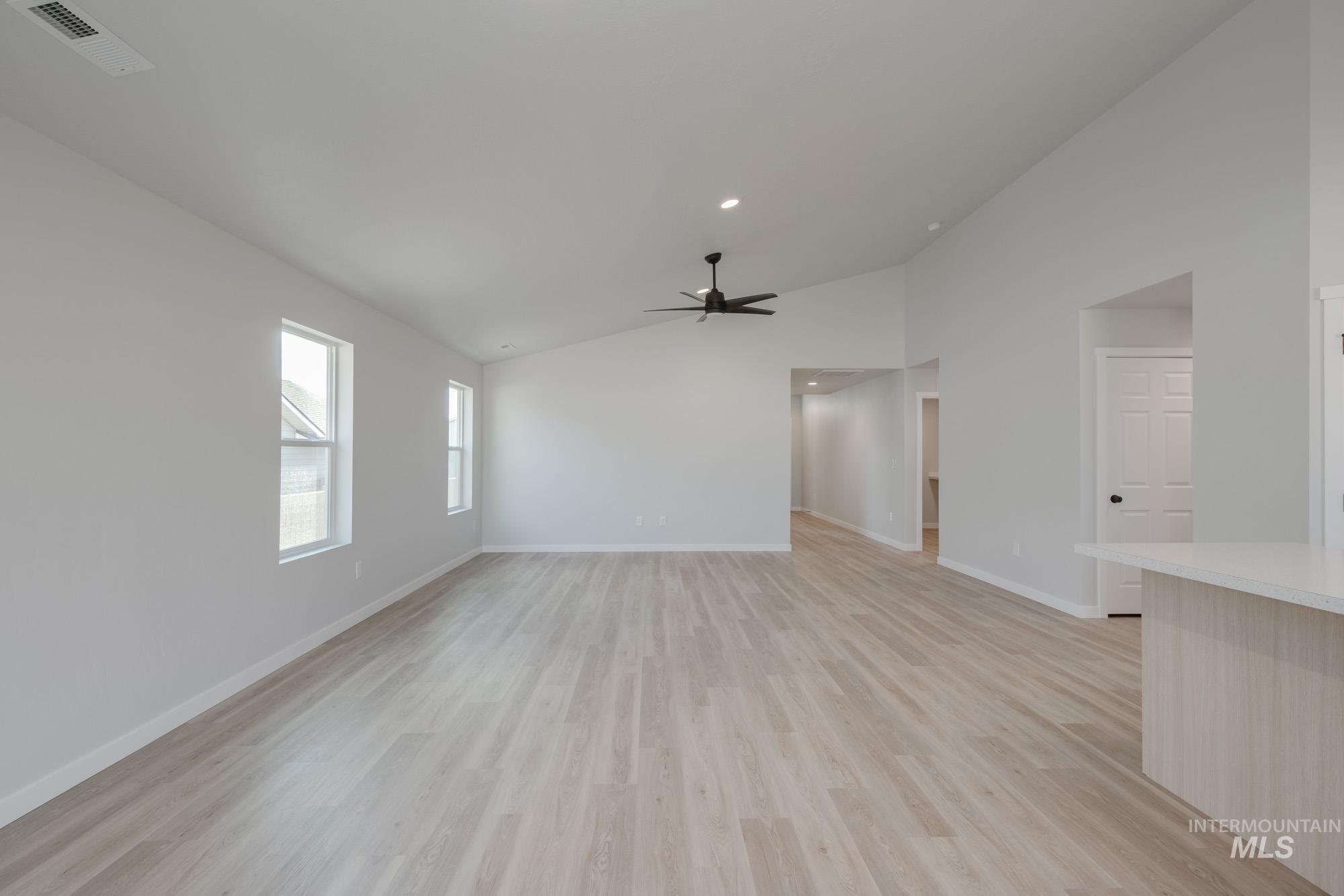 Unfurnished living room with lofted ceiling, light wood-type flooring, and ceiling fan