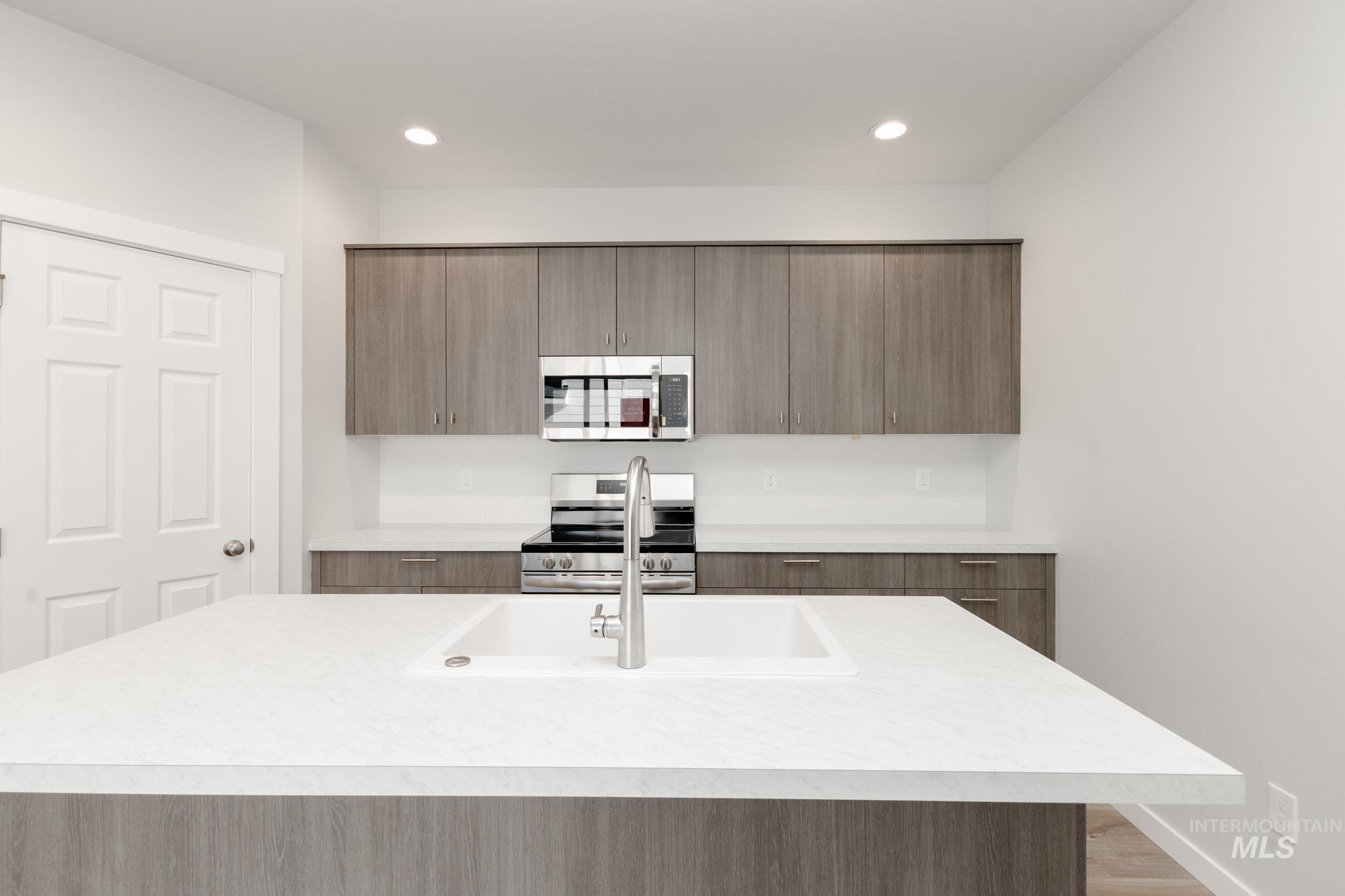 Kitchen featuring modern cabinets, stainless steel appliances, an island with sink, light wood-type flooring, and recessed lighting