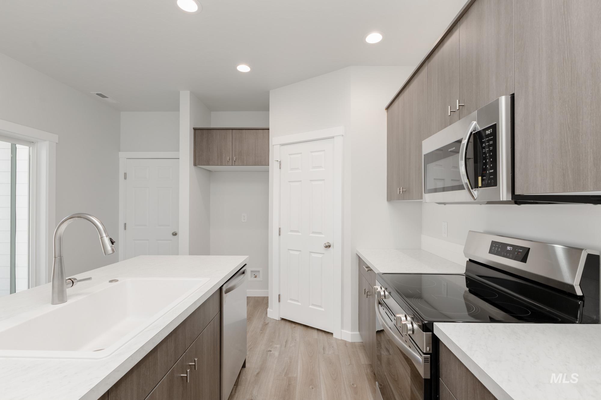 Kitchen with stainless steel appliances, modern cabinets, light wood-style floors, and recessed lighting