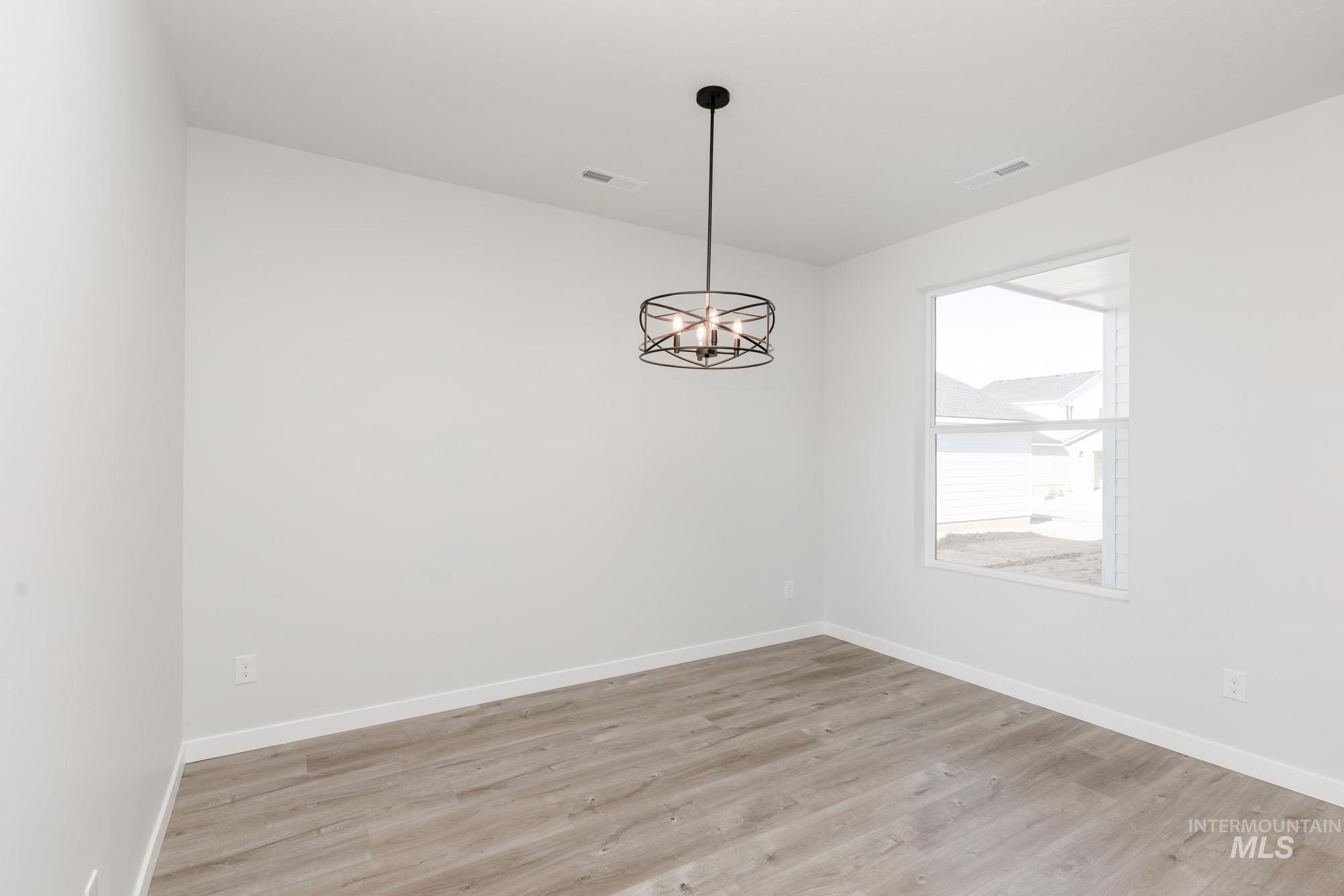 Unfurnished room with a chandelier and light wood-type flooring