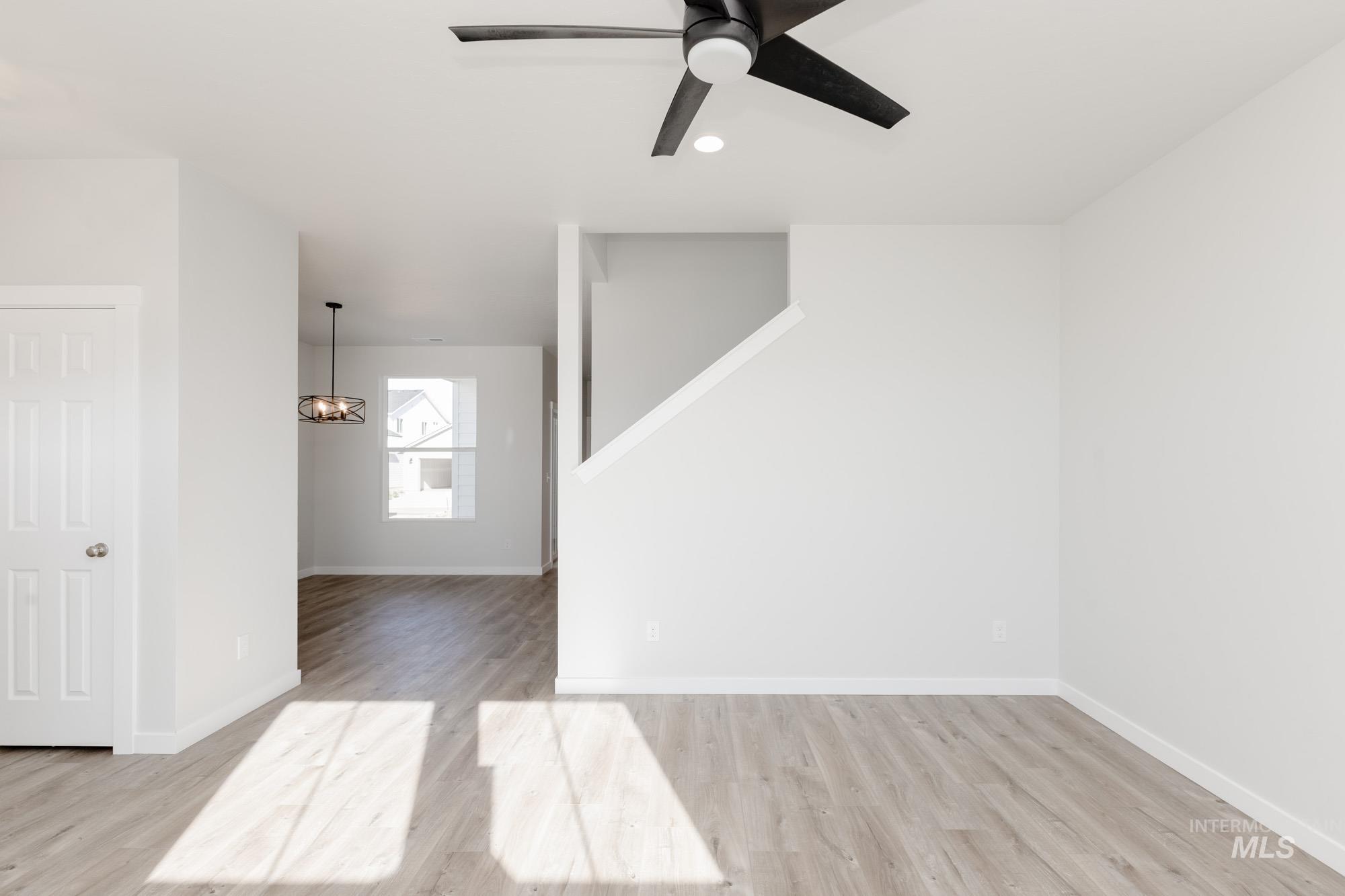 Empty room featuring light wood-style floors, ceiling fan, a chandelier, and recessed lighting