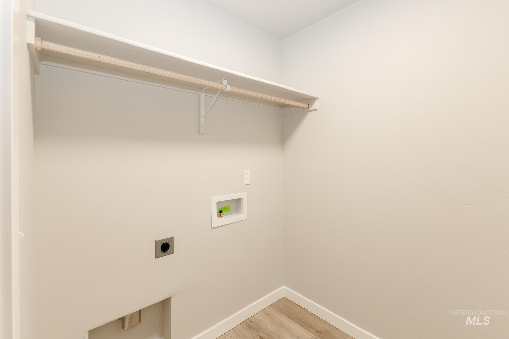 Washroom with light wood finished floors, hookup for an electric dryer, and hookup for a washing machine