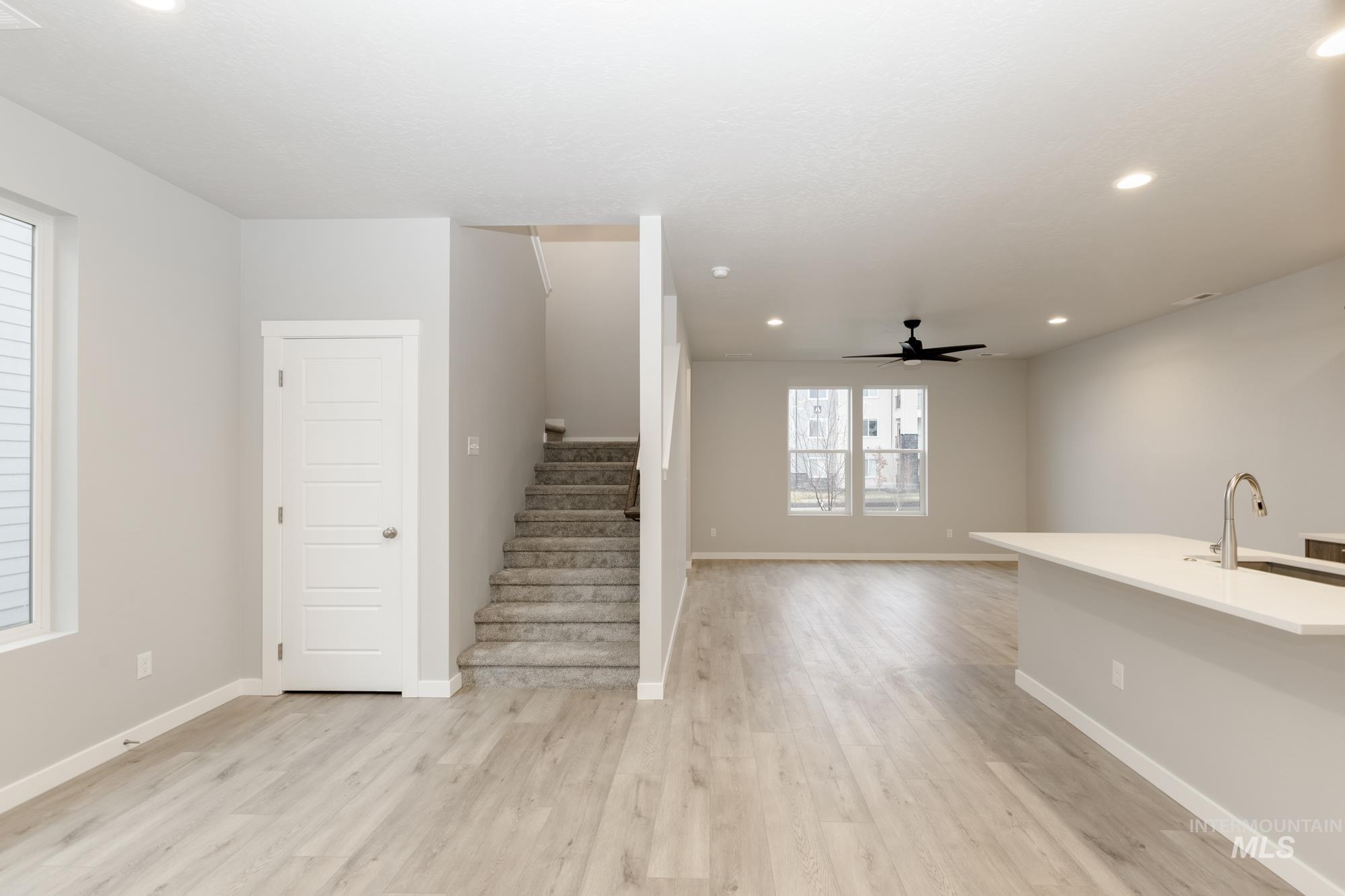 Unfurnished living room featuring recessed lighting, light wood finished floors, stairs, and a ceiling fan