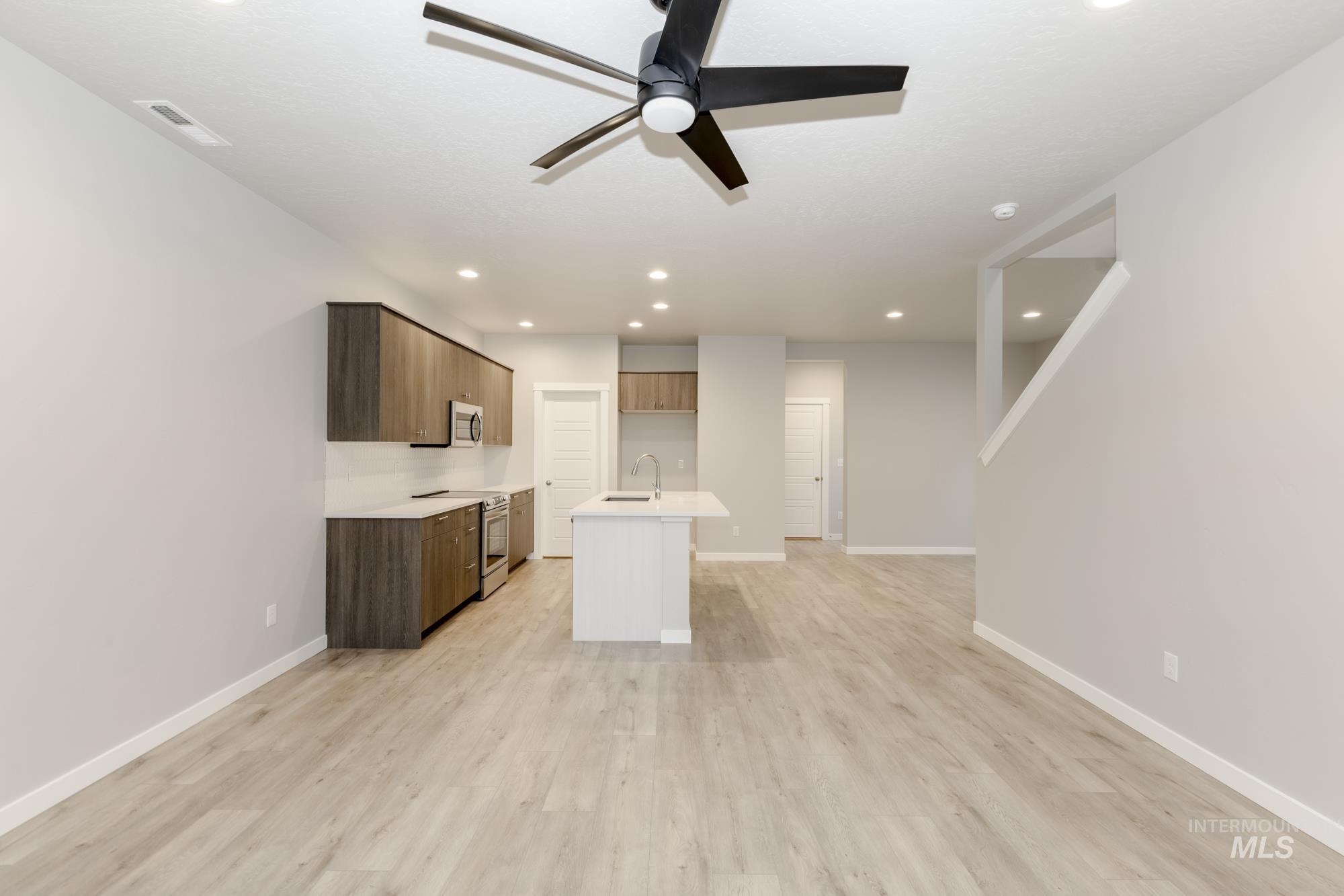 Kitchen with a kitchen island with sink, modern cabinets, stainless steel appliances, open floor plan, and light wood finished floors