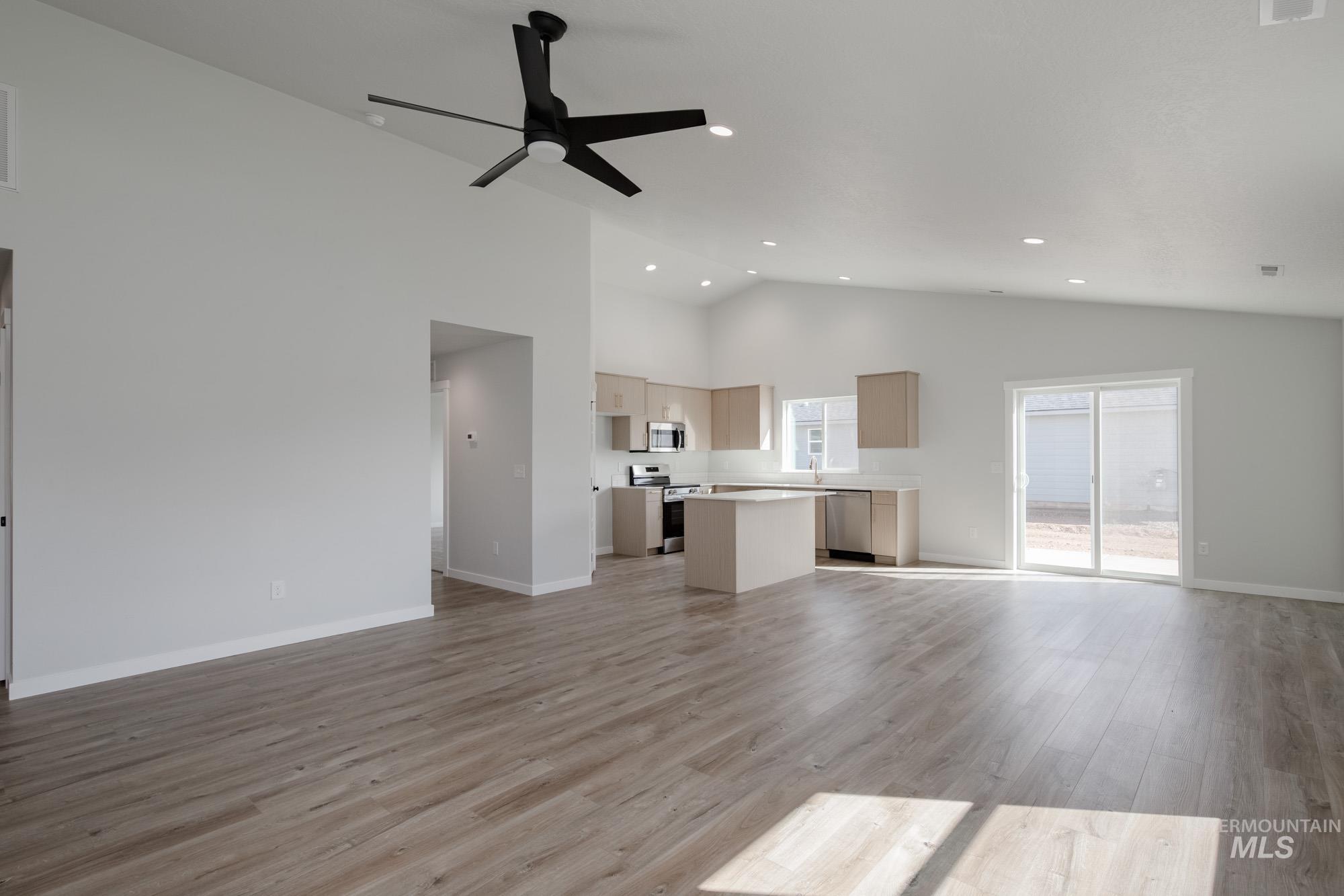 Unfurnished living room featuring light wood-style flooring, a ceiling fan, high vaulted ceiling, and recessed lighting